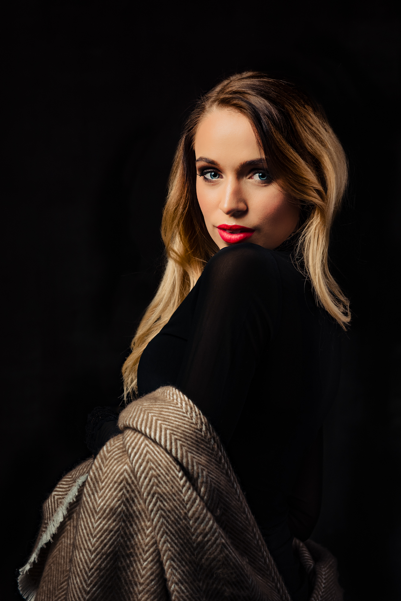 Close studio portrait of a woman with red lipstick and a textured shawl.