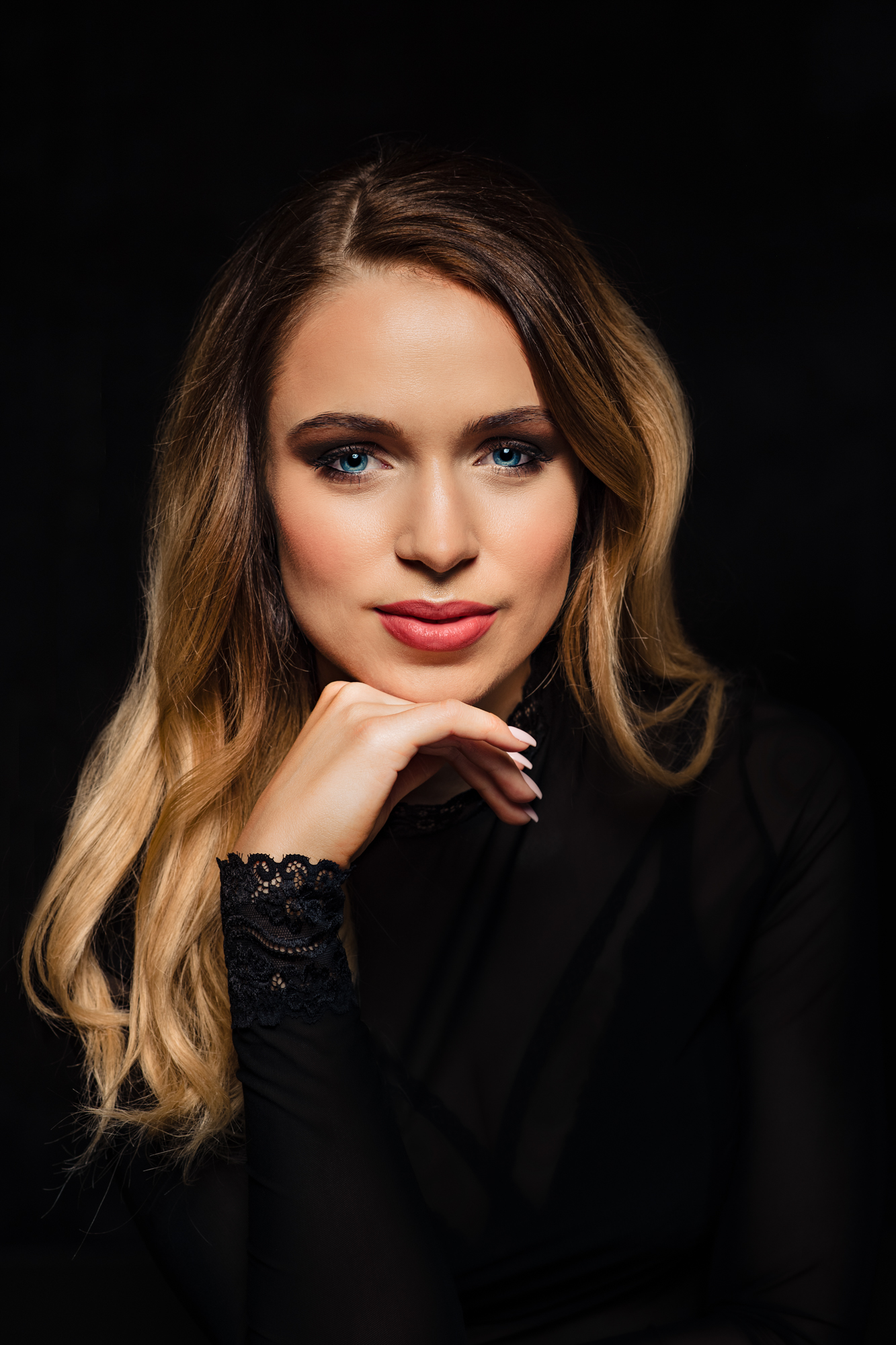 Confident studio portrait with a woman chin resting on her hand.