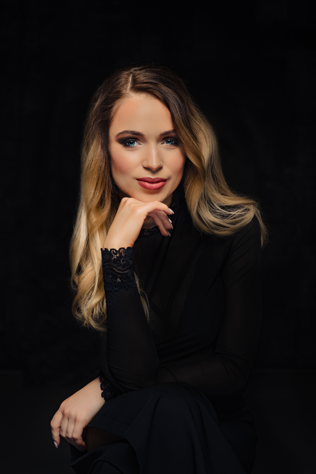 Seated studio portrait session in black clothing and soft light.