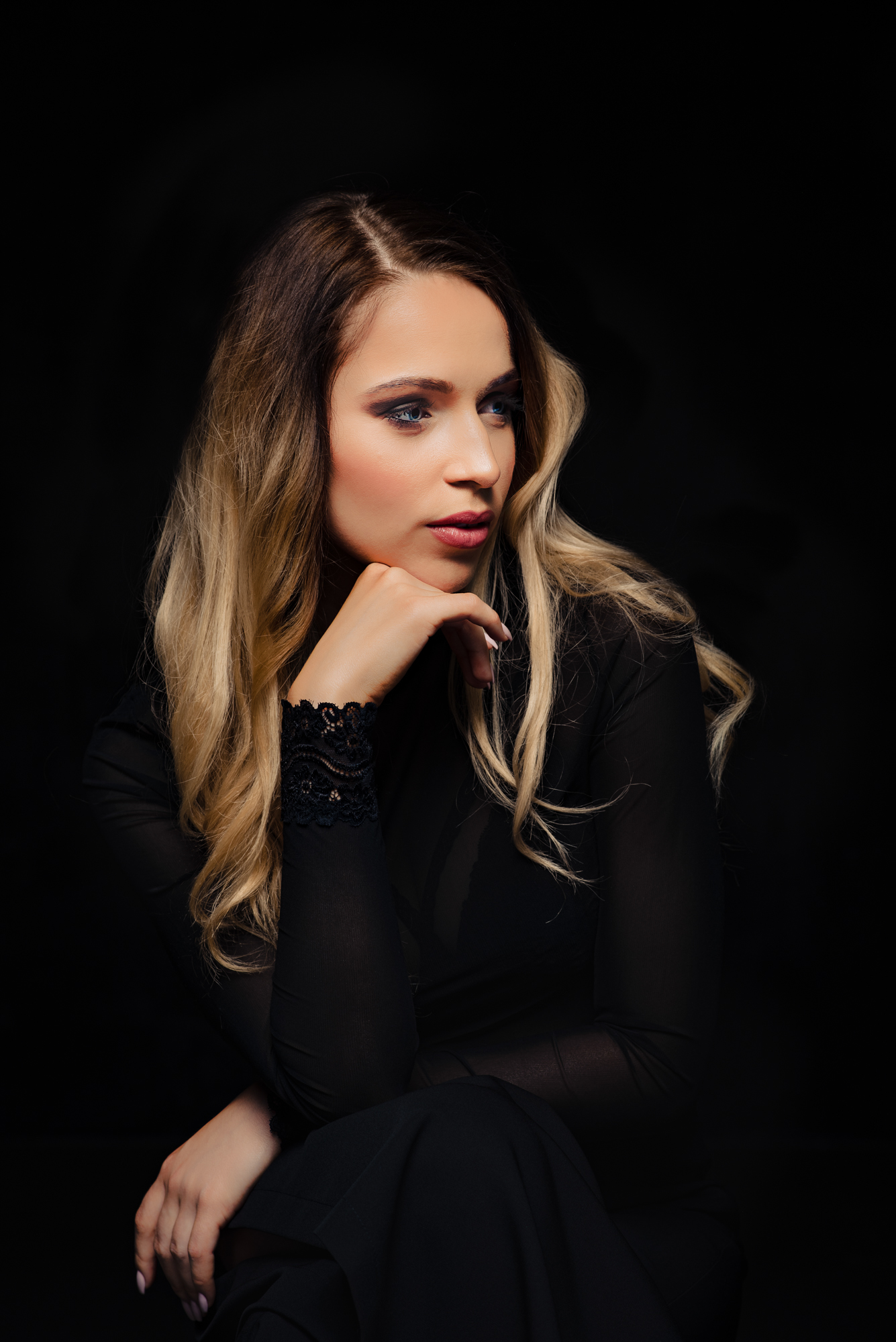 Side-facing studio portrait with lace sleeves and blonde curls.