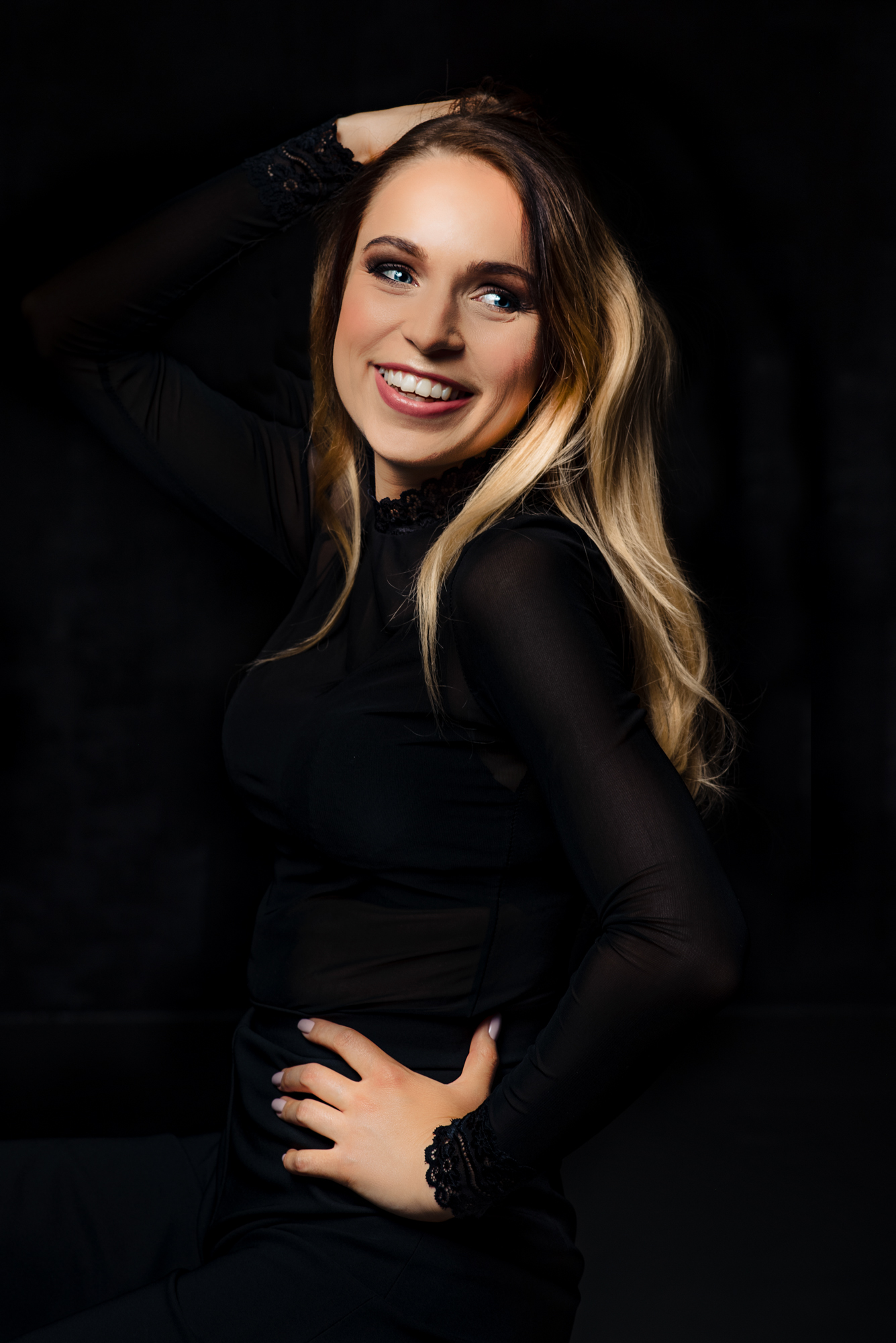 Smiling portrait from a studio session against a dark backdrop.
