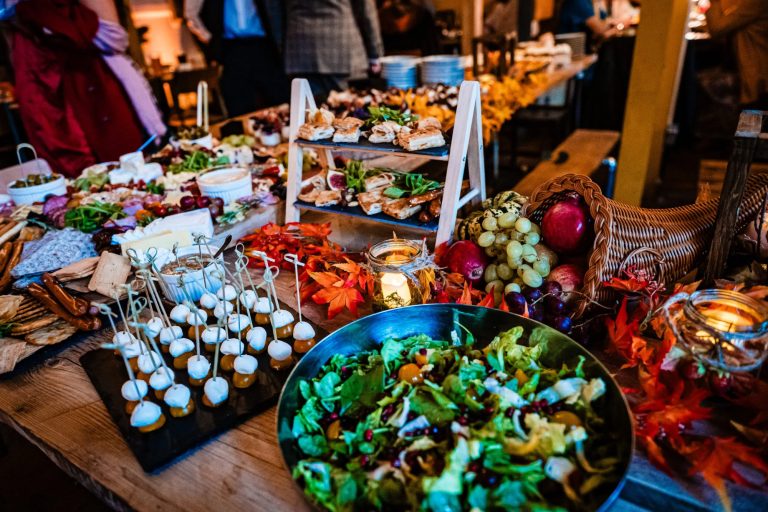 Colourful wedding buffet table with salads, canapés, and autumn decorations during reception dining.