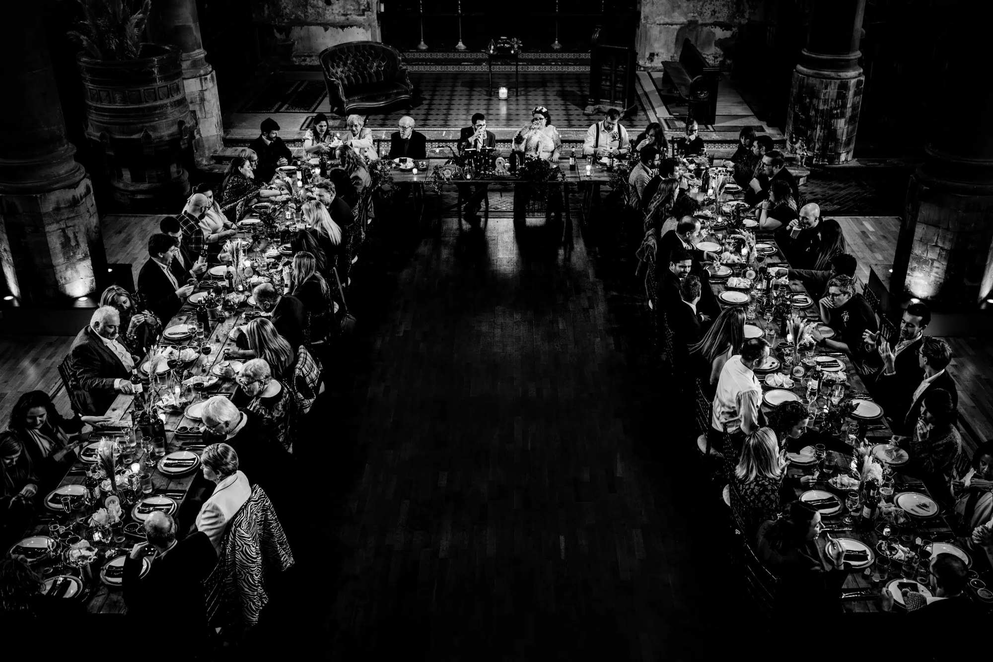 View of wedding breakfast tables inside dramatic church venue setting.