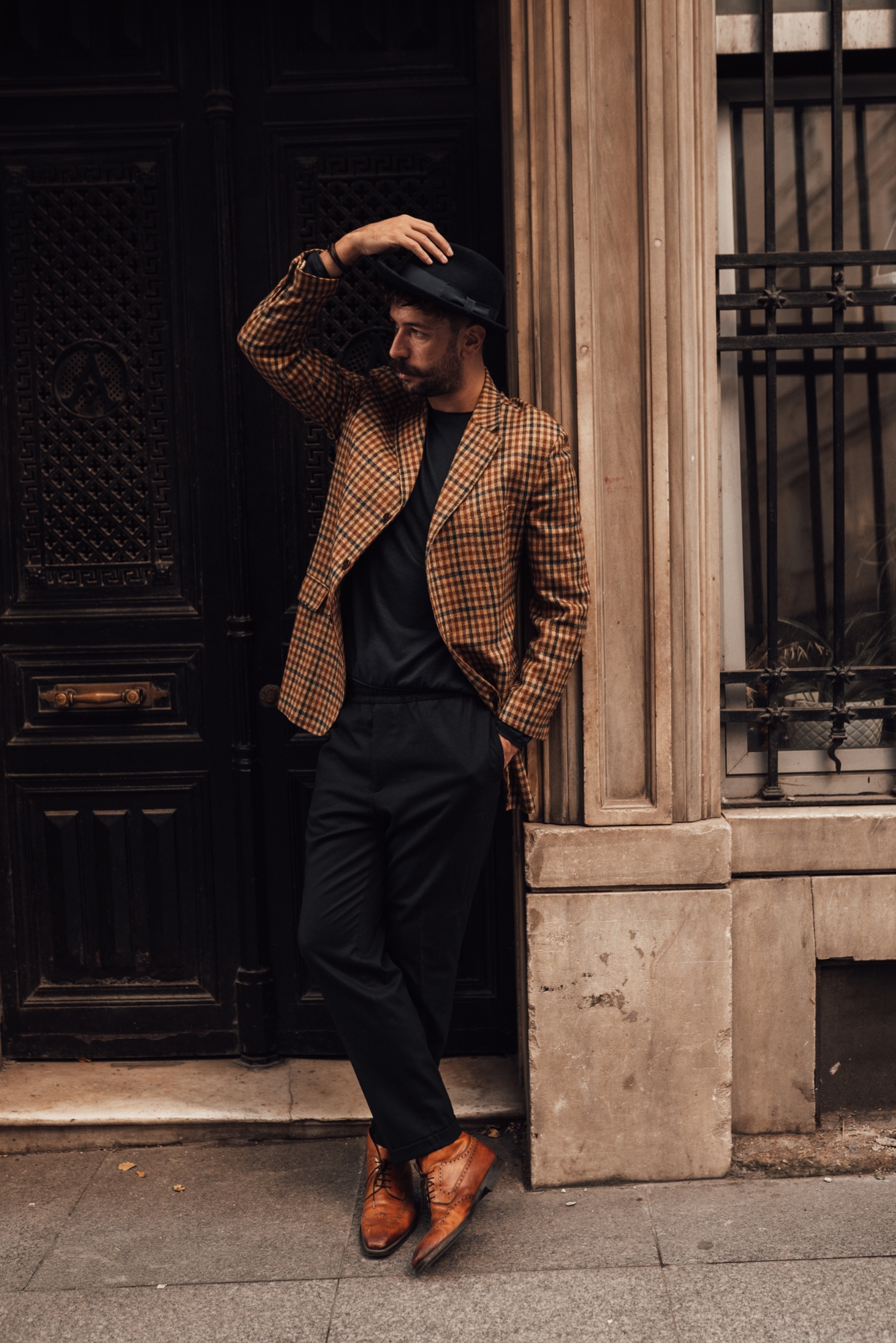 Man wearing checked blazer, hat and leather shoes, stylish but professional wedding photographer outfit example.