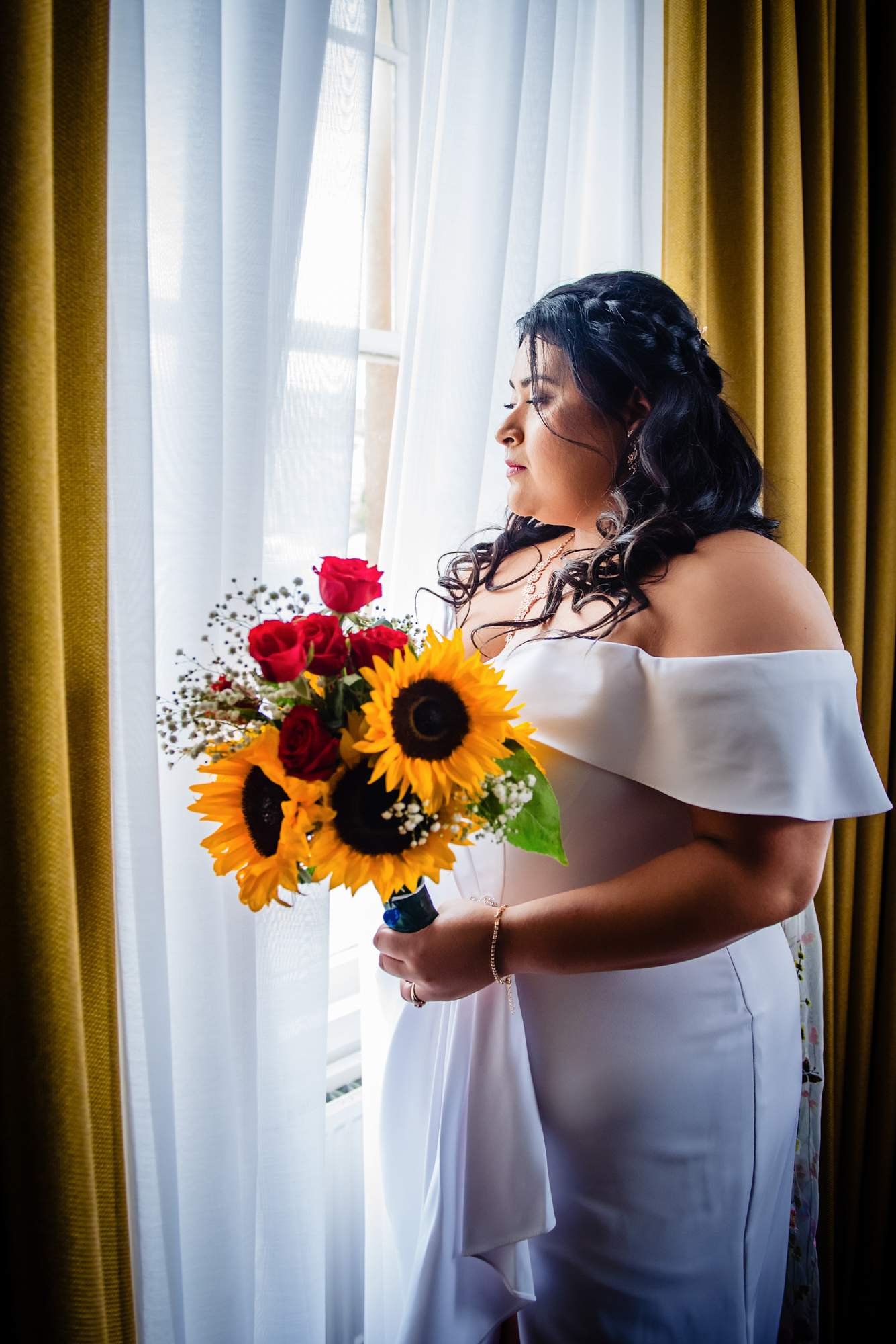 Bride holding sunflower bouquet by window light at Arnos Manor Hotel Bristol wedding.