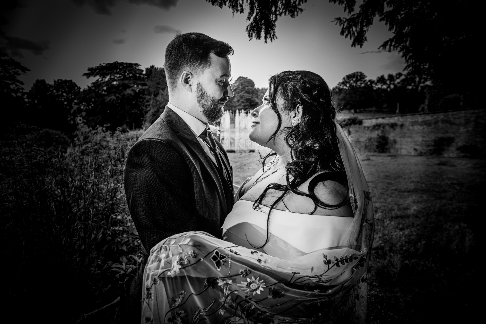 Bride and groom standing close together in Ashton Court gardens Bristol.