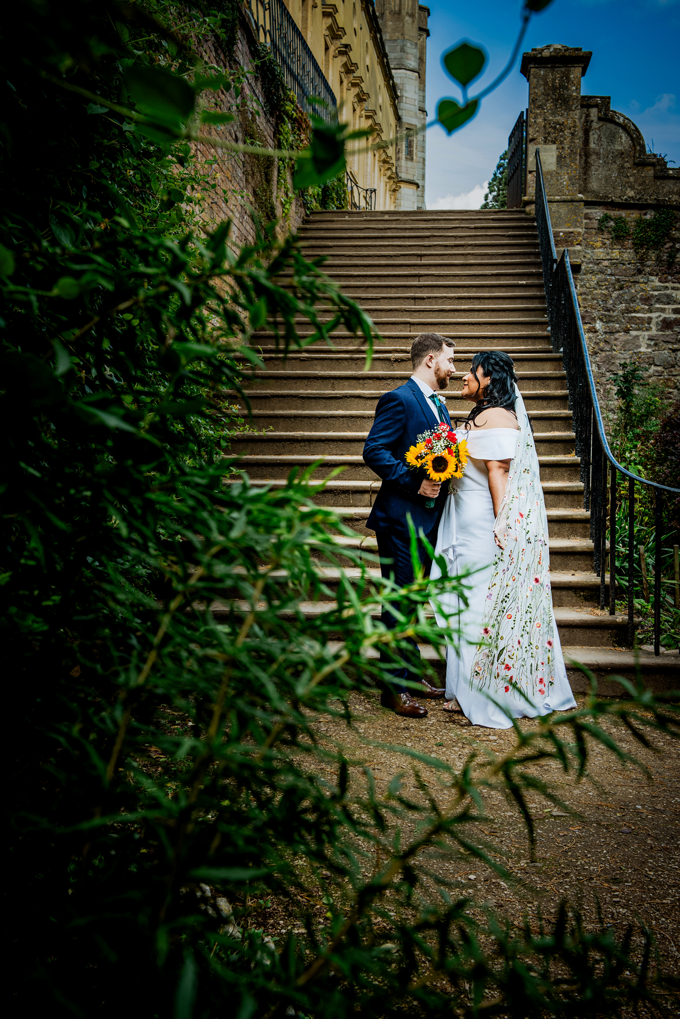 Bride and groom standing by stone staircase at Ashton Court.