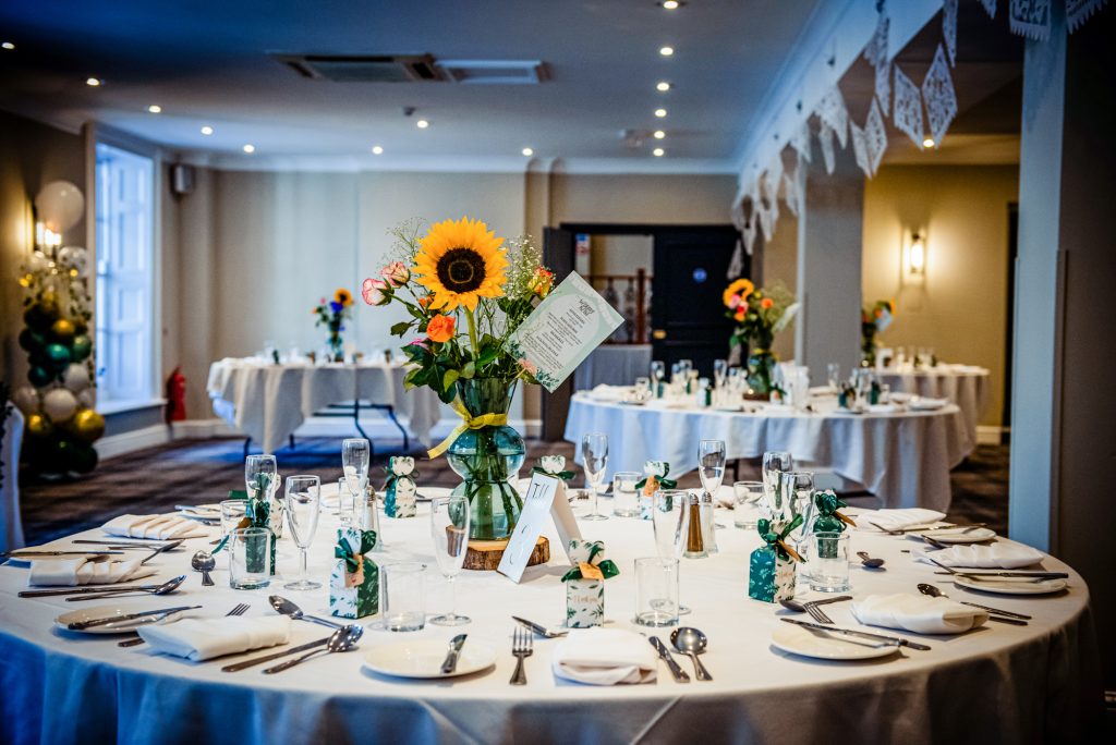 Wedding reception room with round tables and floral centrepieces at Arnos Manor Bristol.