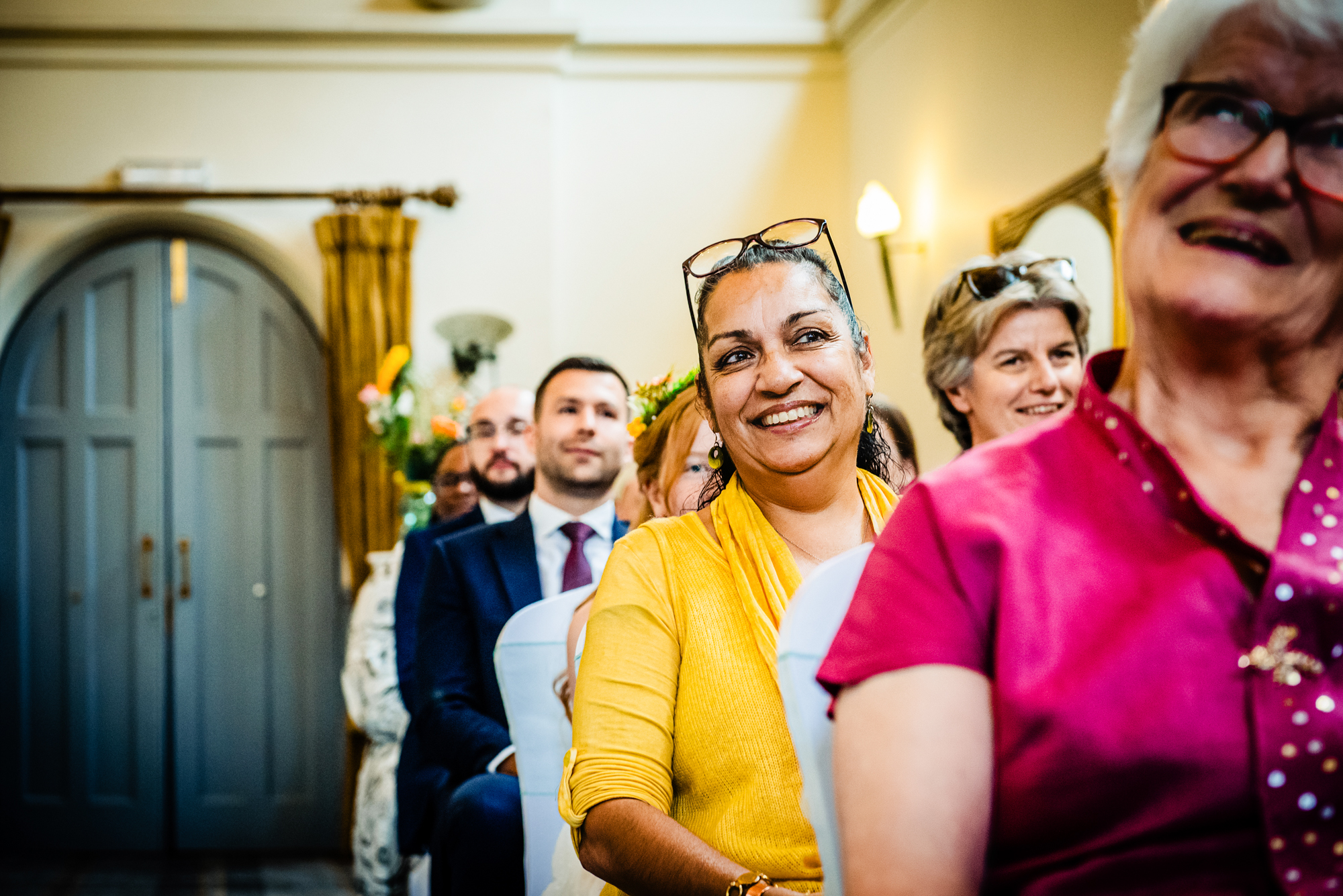 Smiling wedding guests seated during ceremony at Arnos Manor Bristol indoor wedding.
