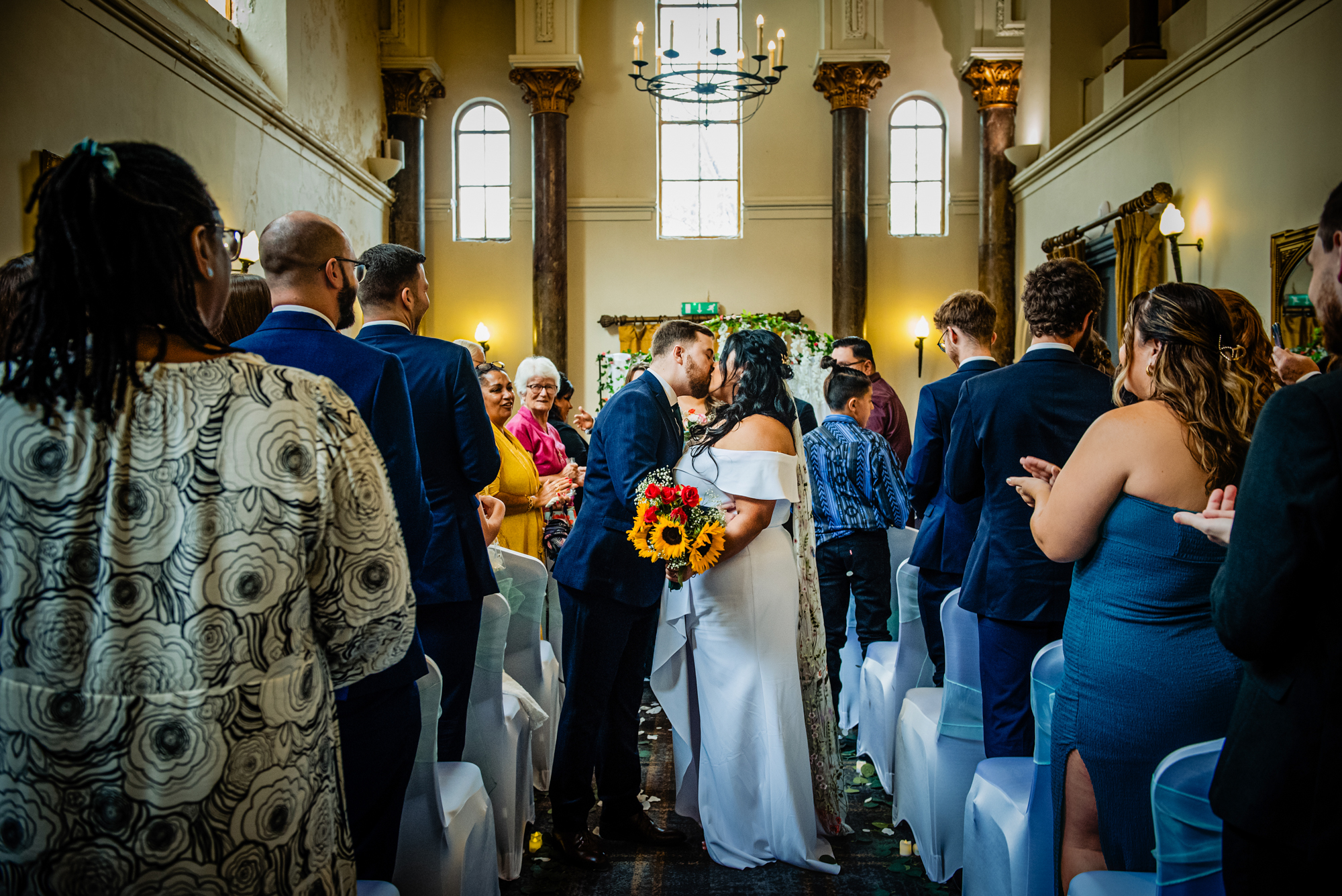 Wide shot of couple kissing during ceremony surrounded by guests at Arnos Manor Hotel in Bristol.