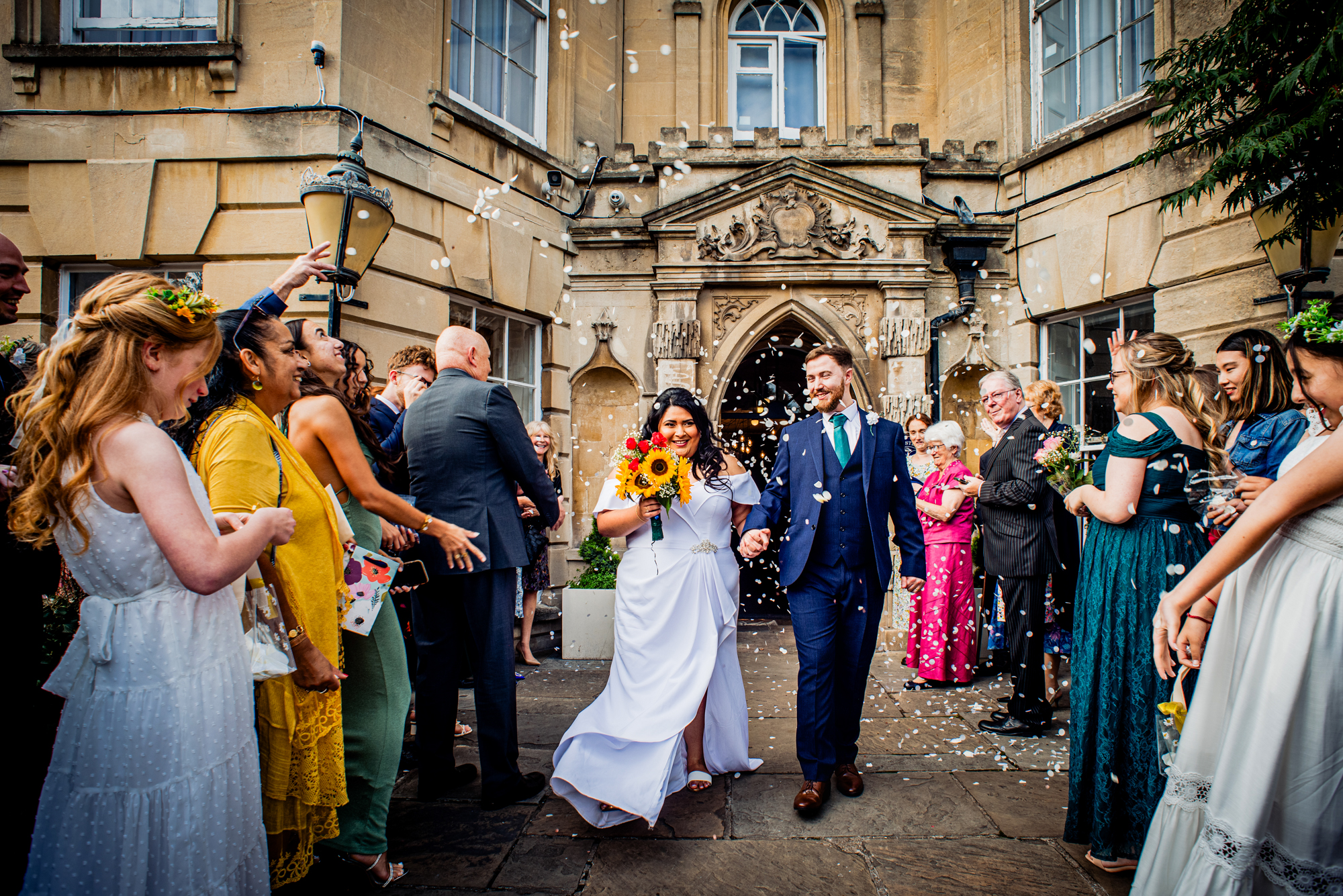 Confetti exit outside Arnos Manor Hotel with guests celebrating around couple.