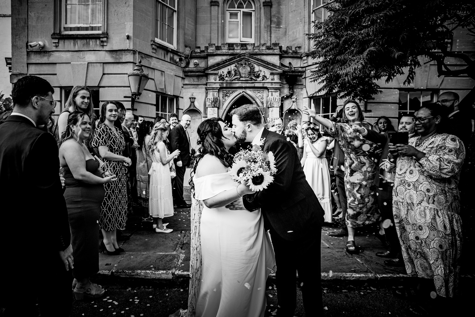 Couple kissing during confetti exit outside Arnos Manor Hotel wedding venue in Bristol.
