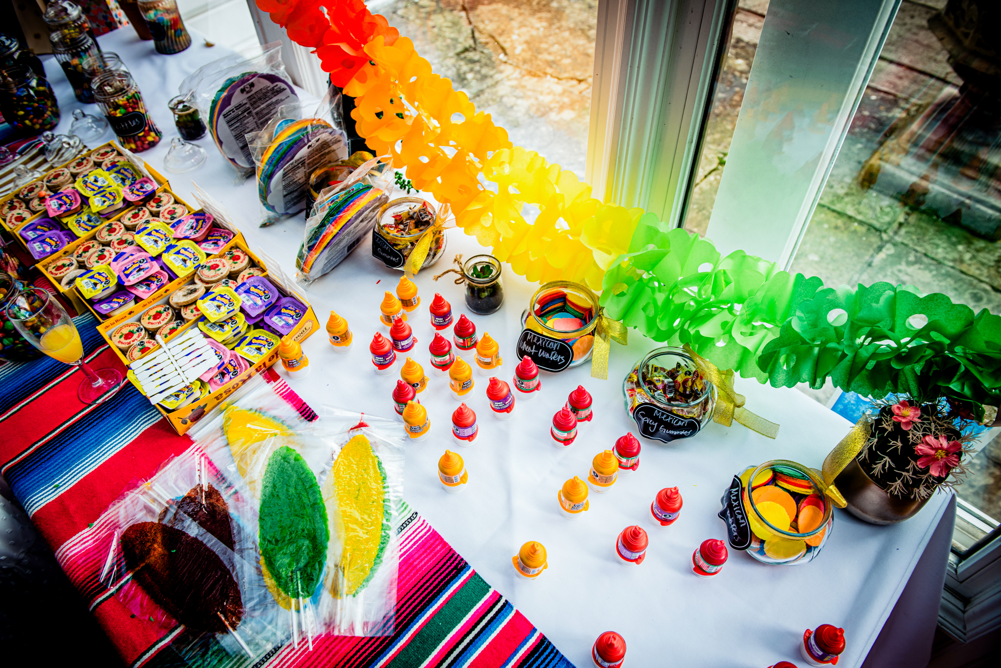 Bright Mexican-style wedding sweet table with rainbow decorations and treats.