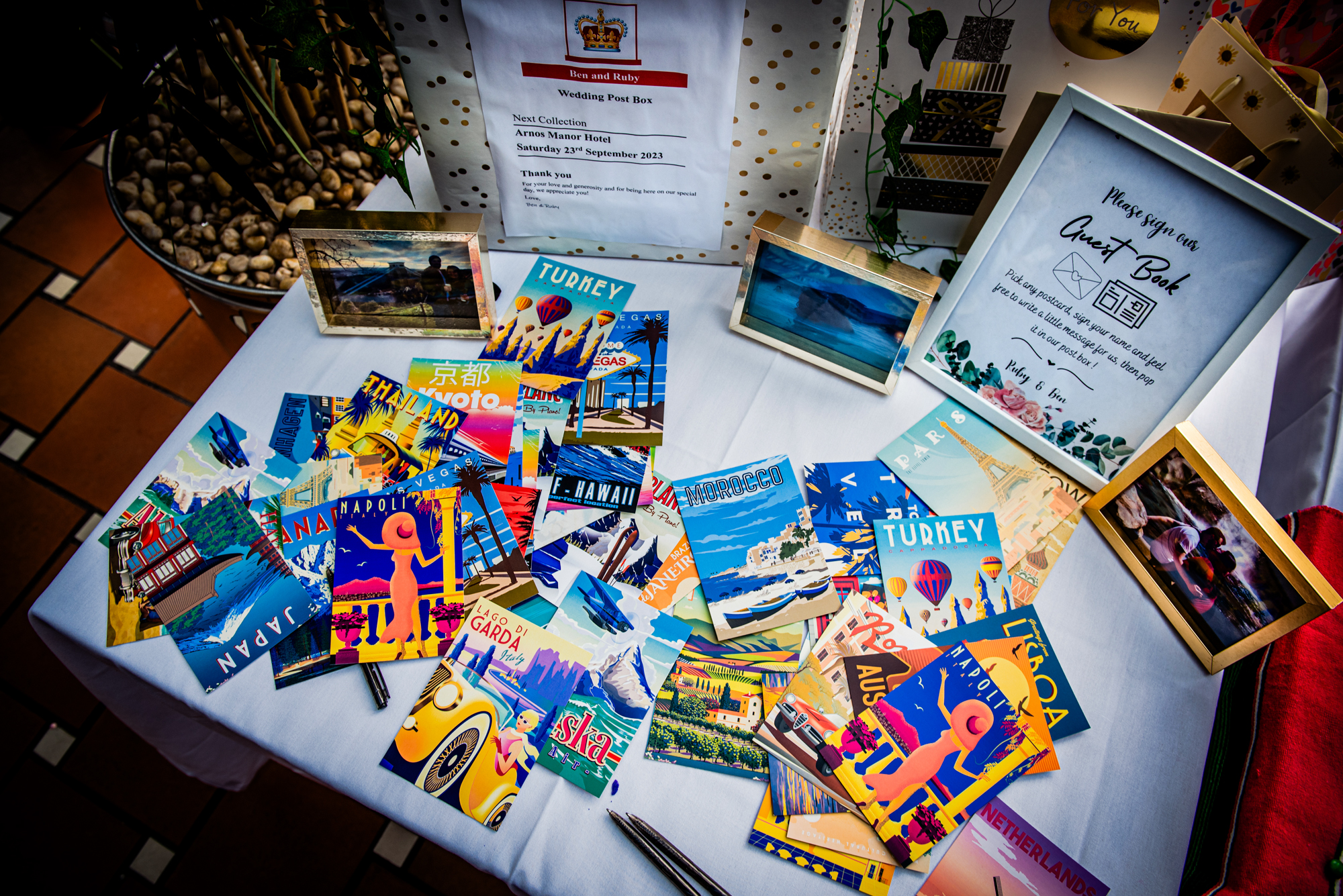 Wedding guest book table with travel postcards and framed photos.