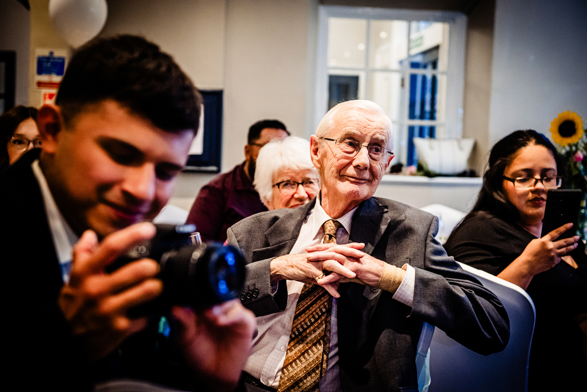 Elderly guest watching emotional moment during wedding ceremony.