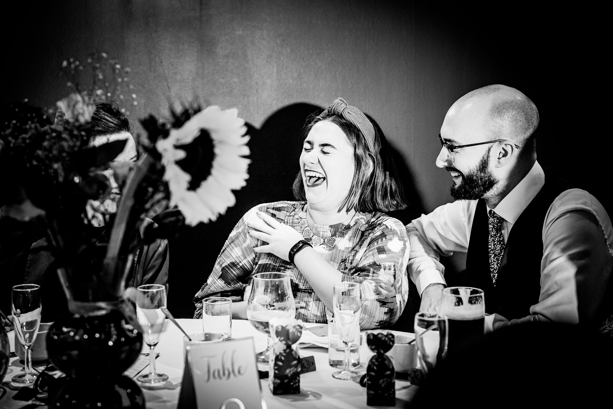 Guests laughing together during lively wedding reception speech.