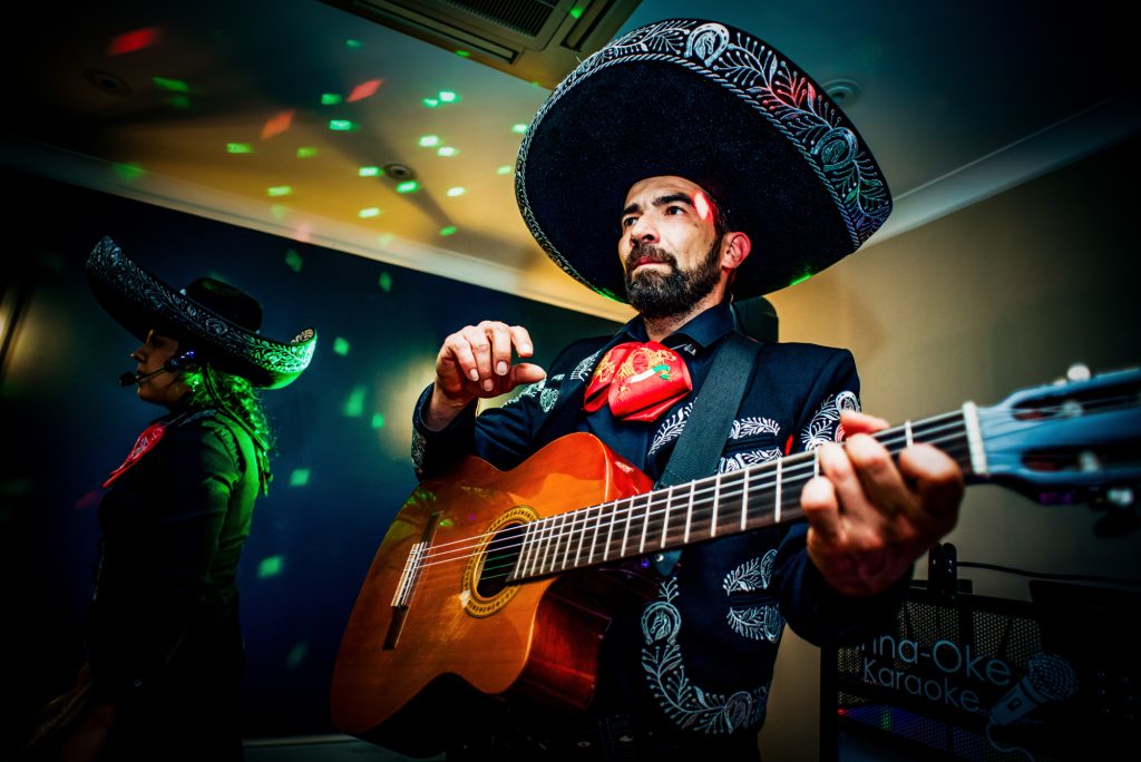 Mariachi guitarist performing under colourful lights during evening wedding entertainment.