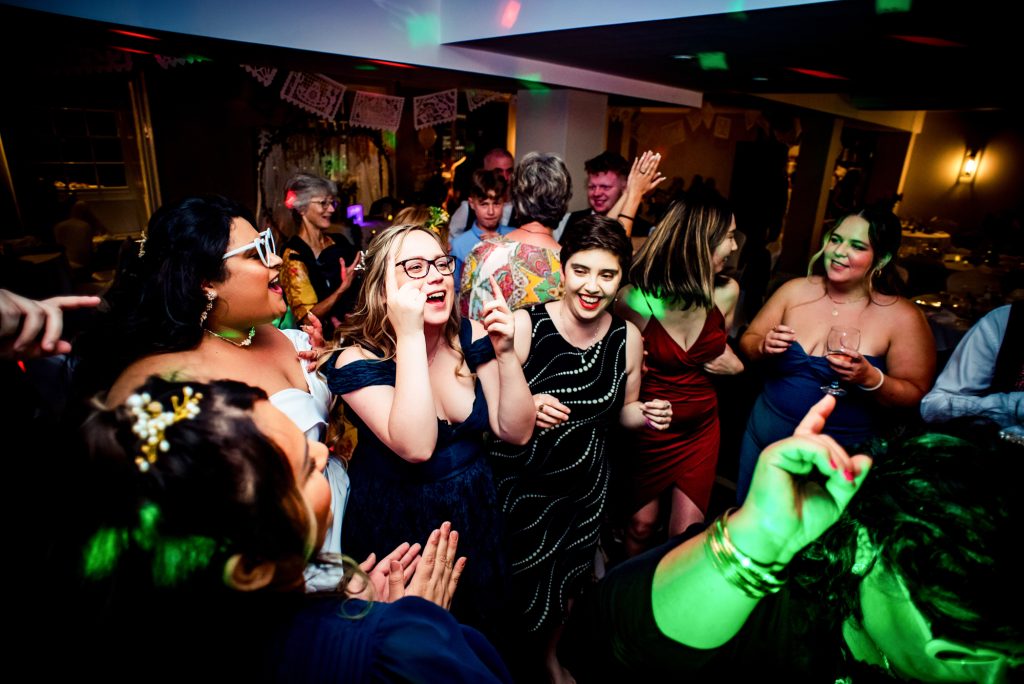 Guests and bride dancing with energetic movements on the dance floor.