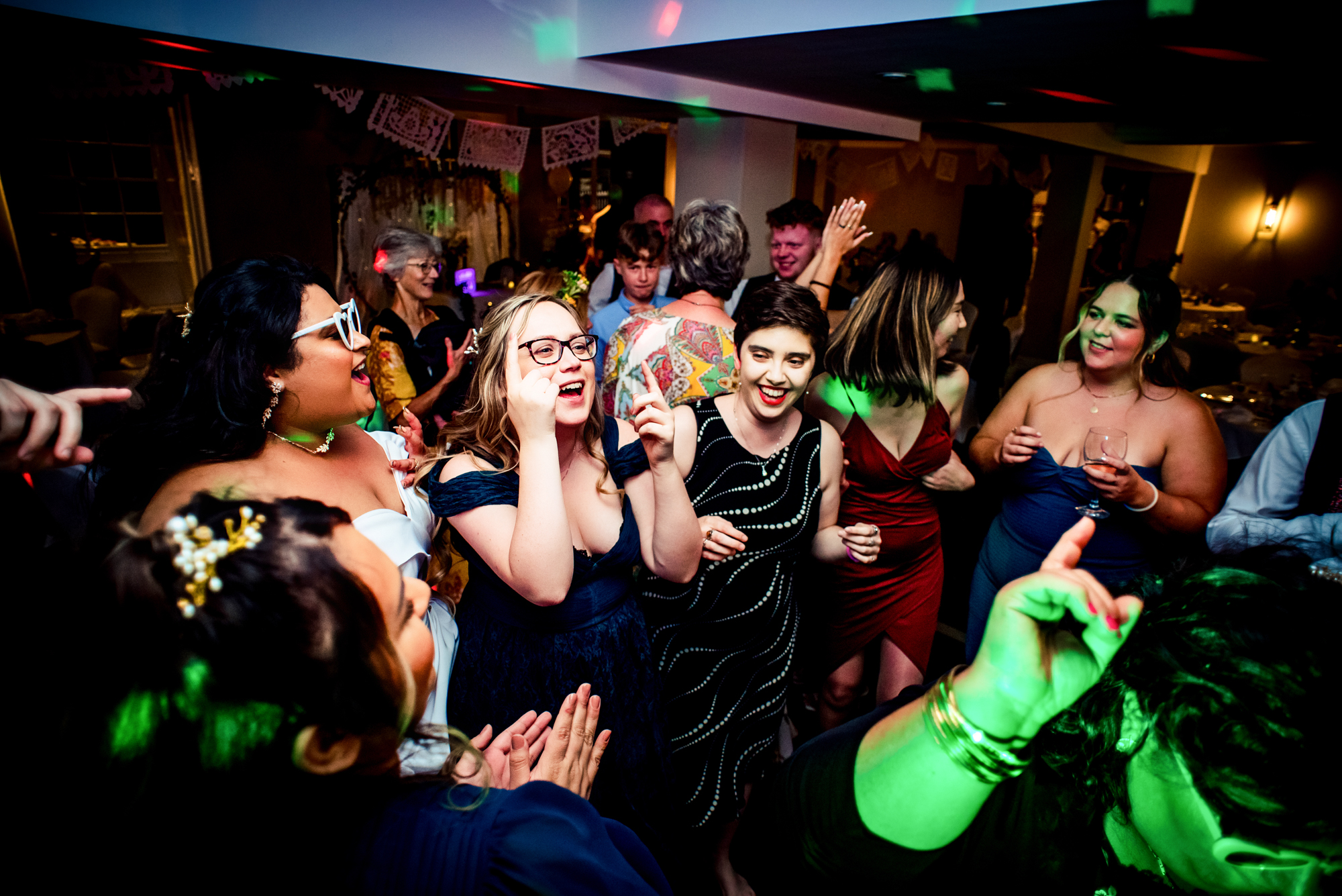 Guests and bride dancing with energetic movements on the dance floor.