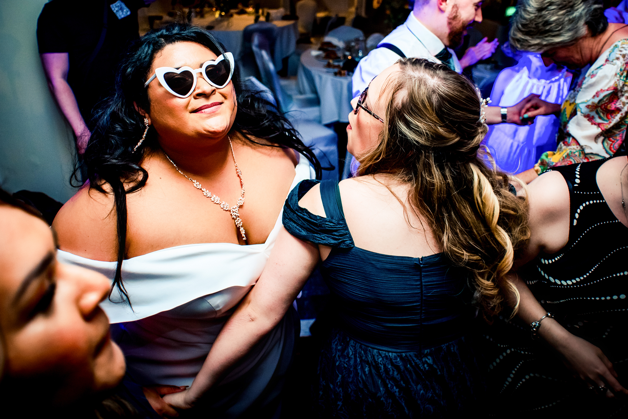 Guests laughing and dancing closely together during fun and energetic wedding moment.