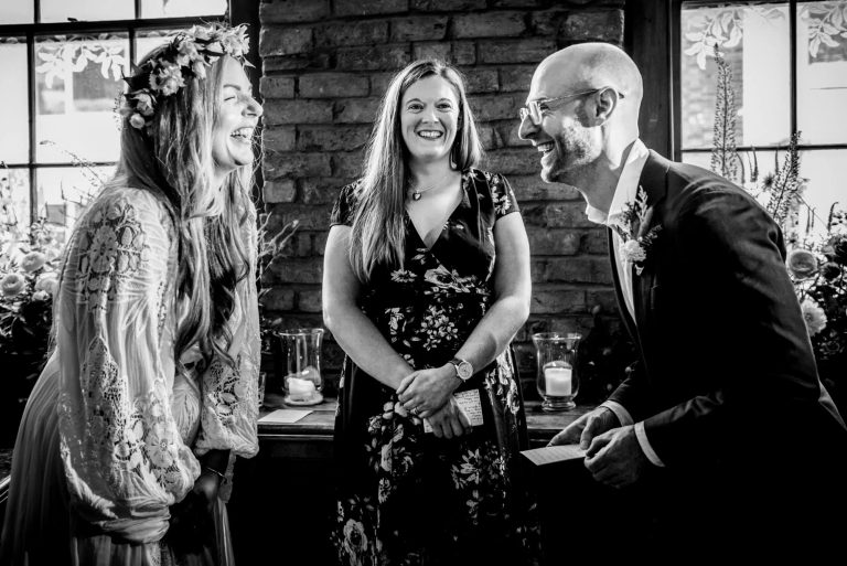 Couple laughing with officiant during relaxed indoor wedding ceremony in Bristol.