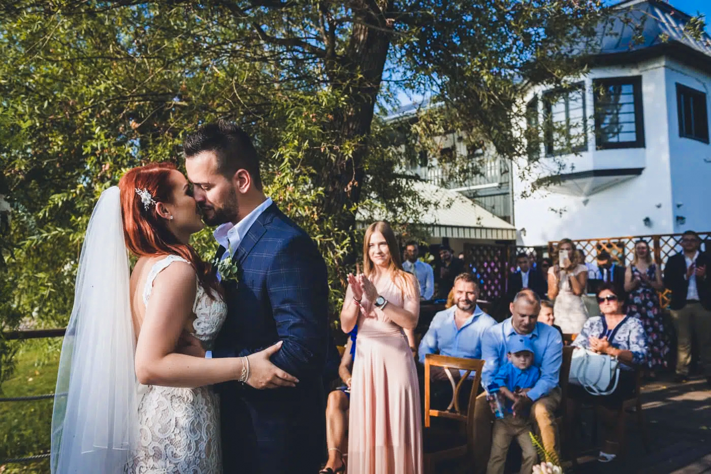 Bride and groom sharing first kiss during outdoor garden wedding ceremony.