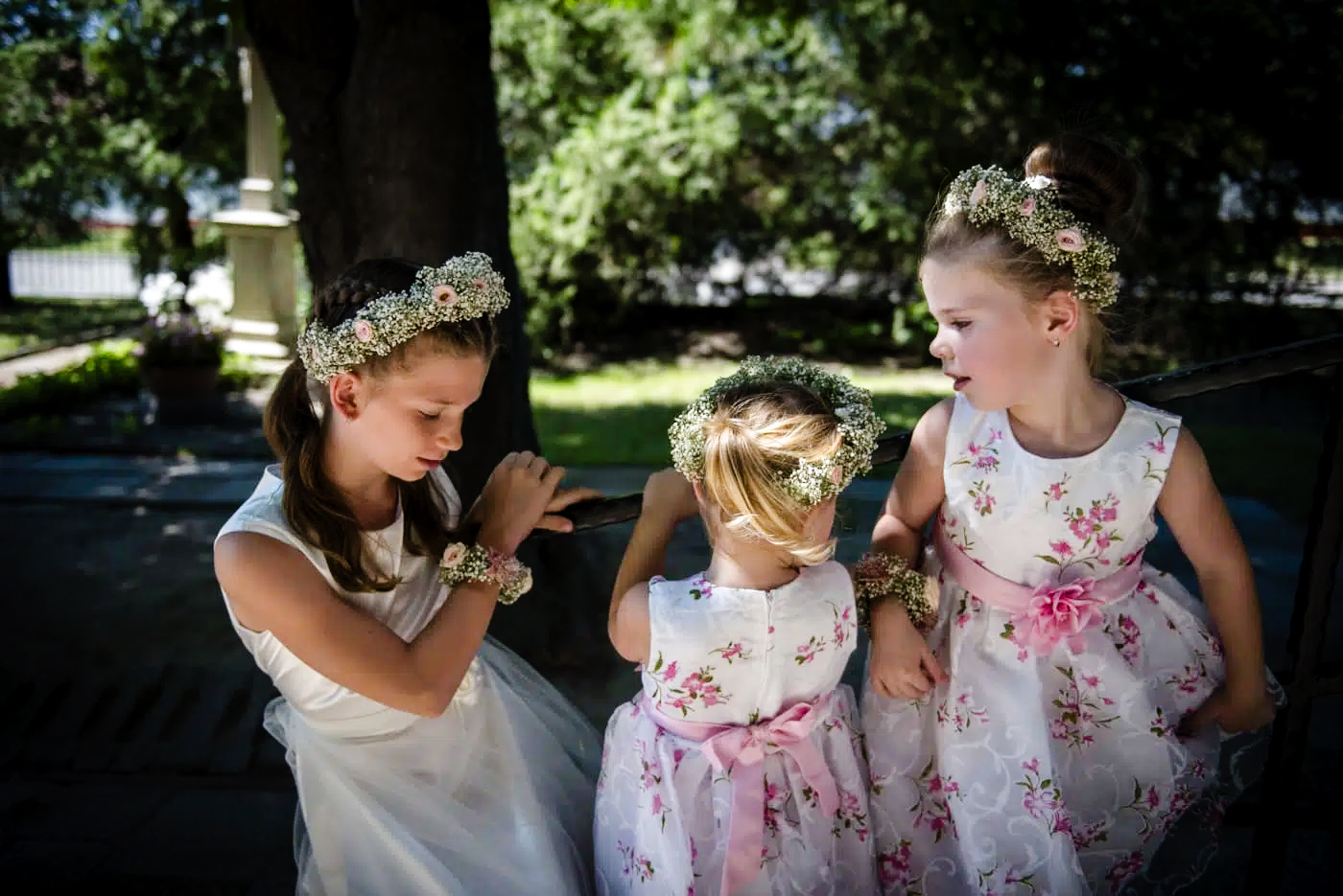 Flower girls wearing matching floral crowns and dresses before wedding ceremony.
