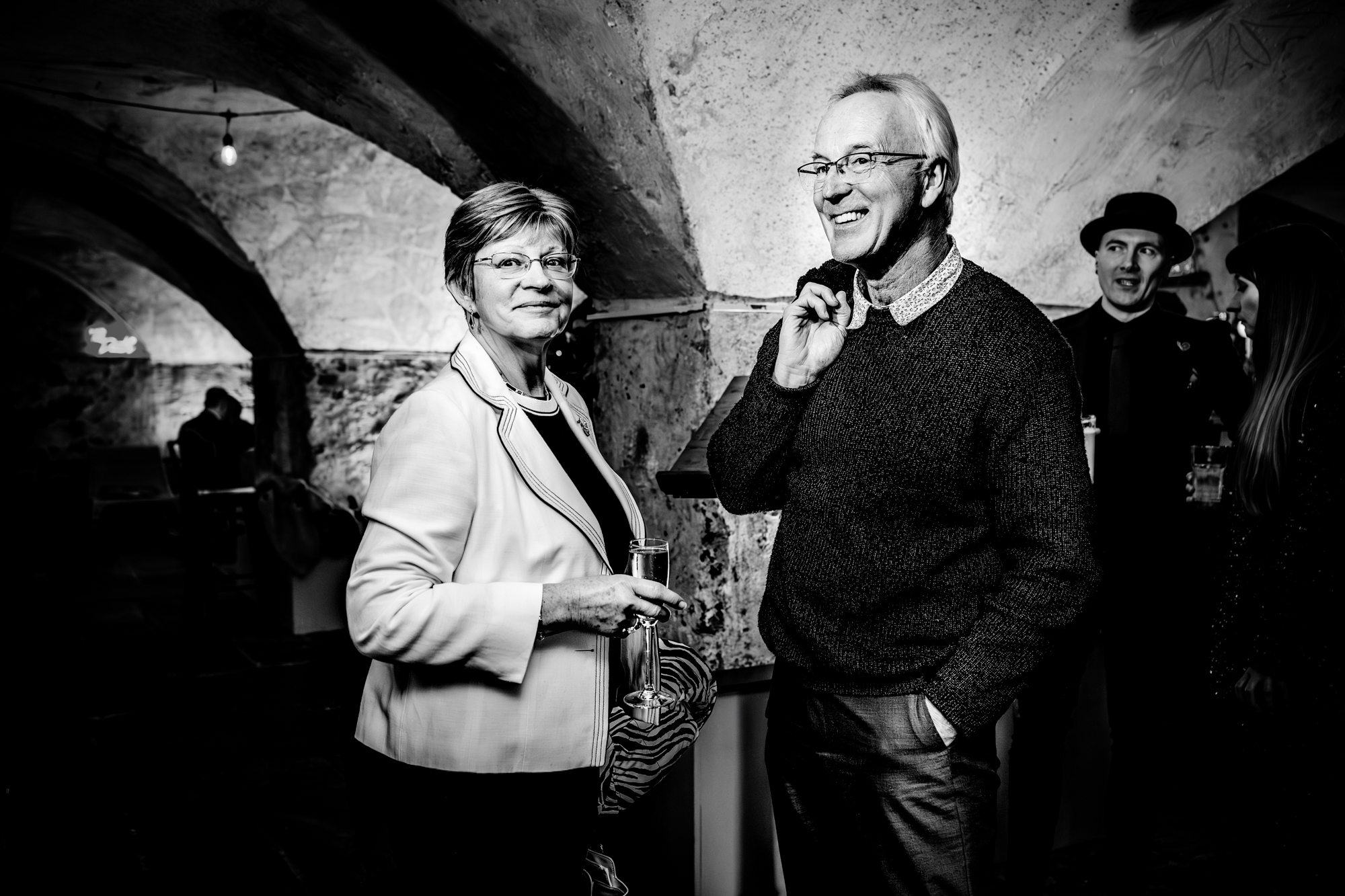Wedding guests smiling and holding drinks in atmospheric vaulted space