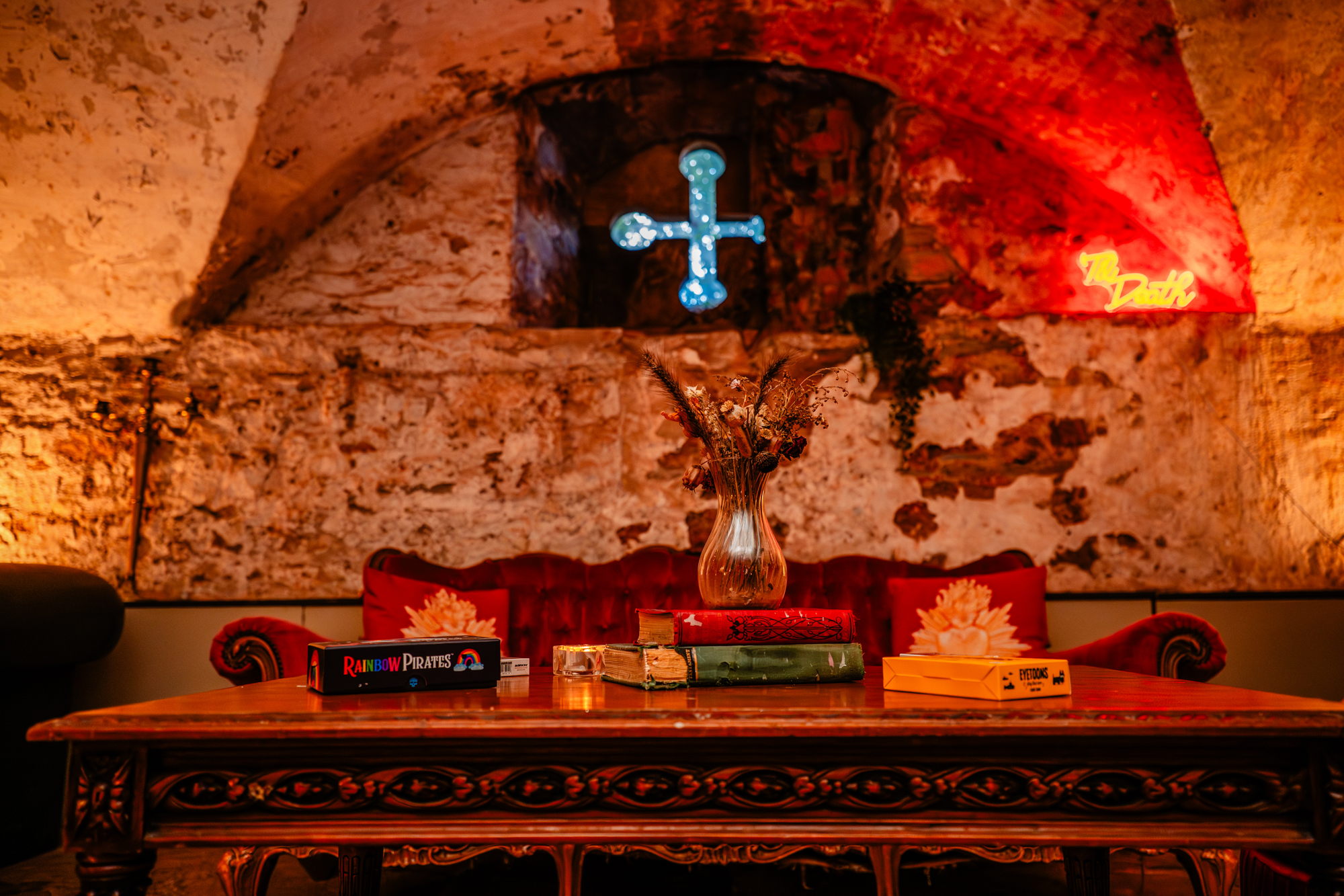 Styled reception table with vintage books, dried flowers and candles beneath arched stone walls at The Mount Without Bristol.