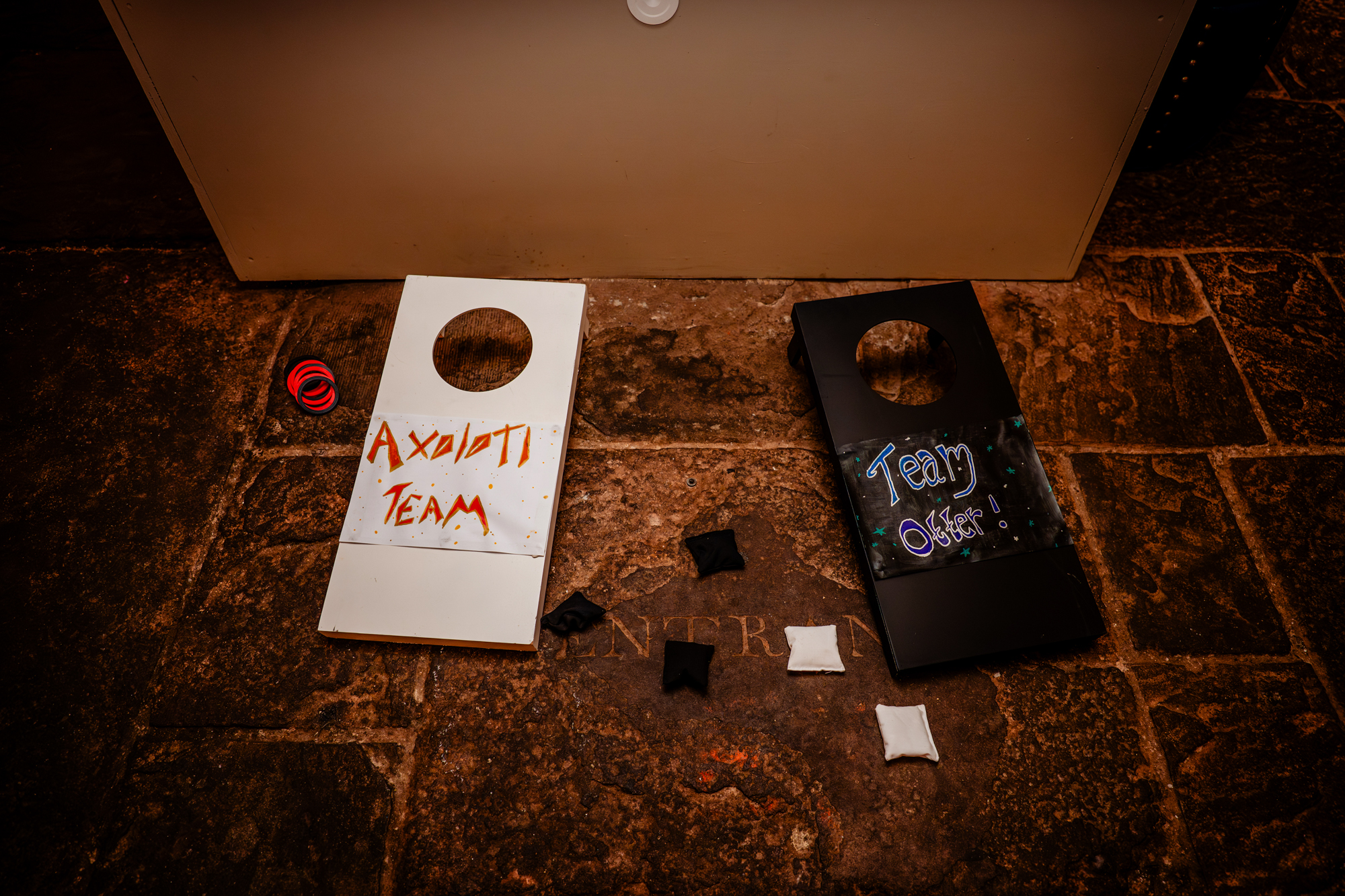 Cornhole wedding games labelled “Axolotl Team” and “Team Otter” arranged on stone floor at The Mount Without Bristol.