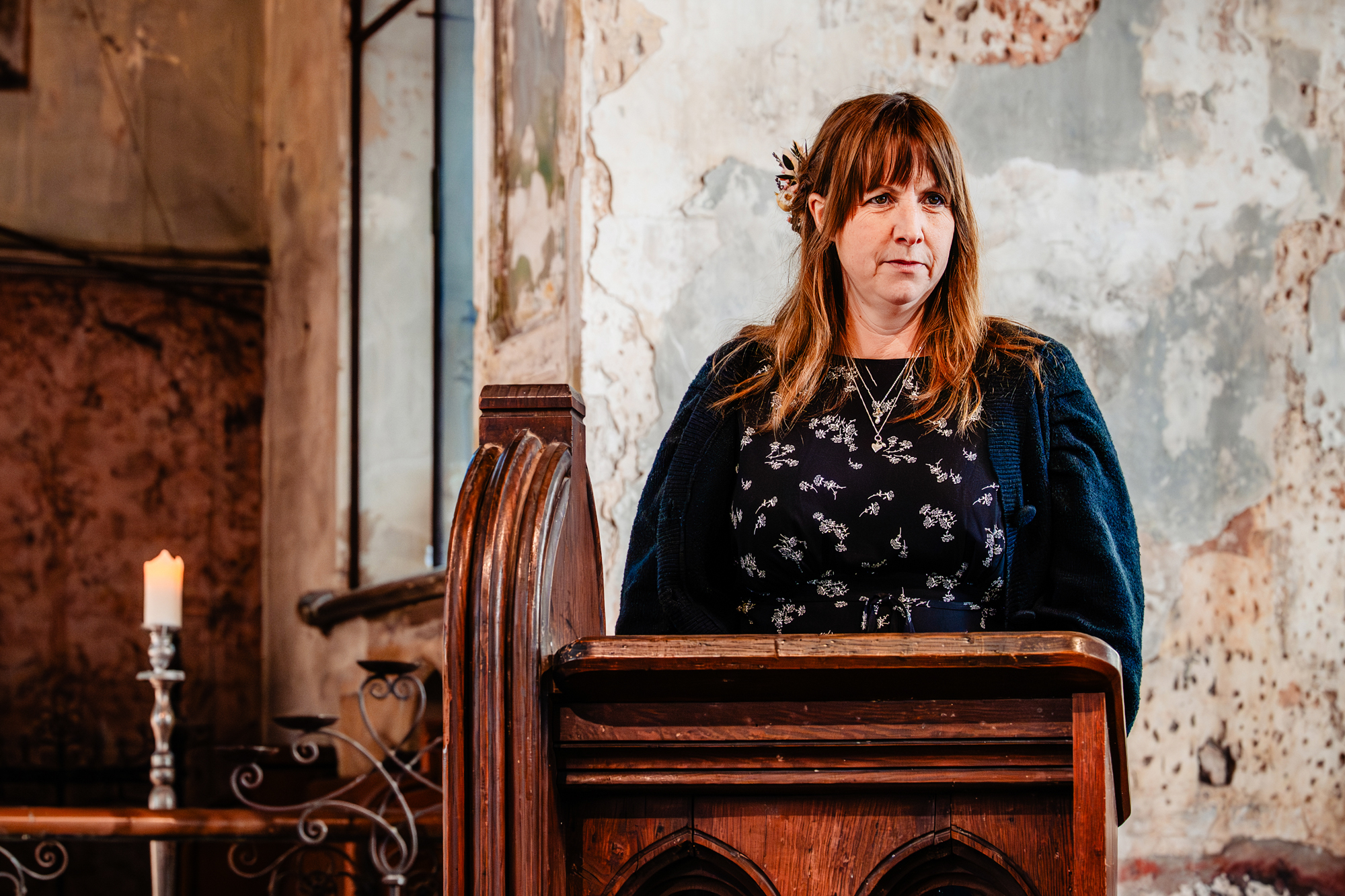 Wedding guest reading during ceremony in historic textured interior space.