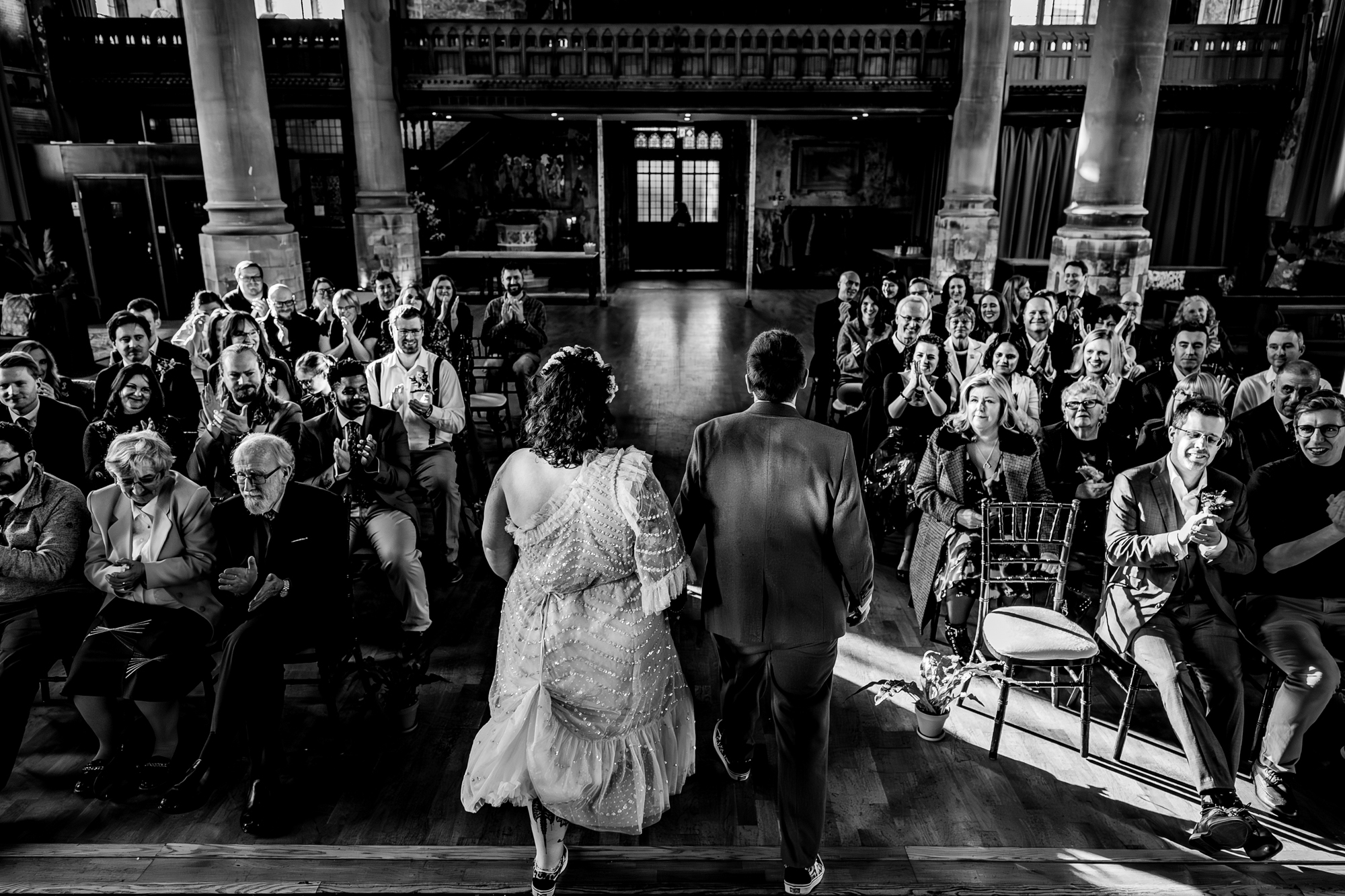 Wide ceremony scene with guests applauding inside historic Bristol wedding venue.