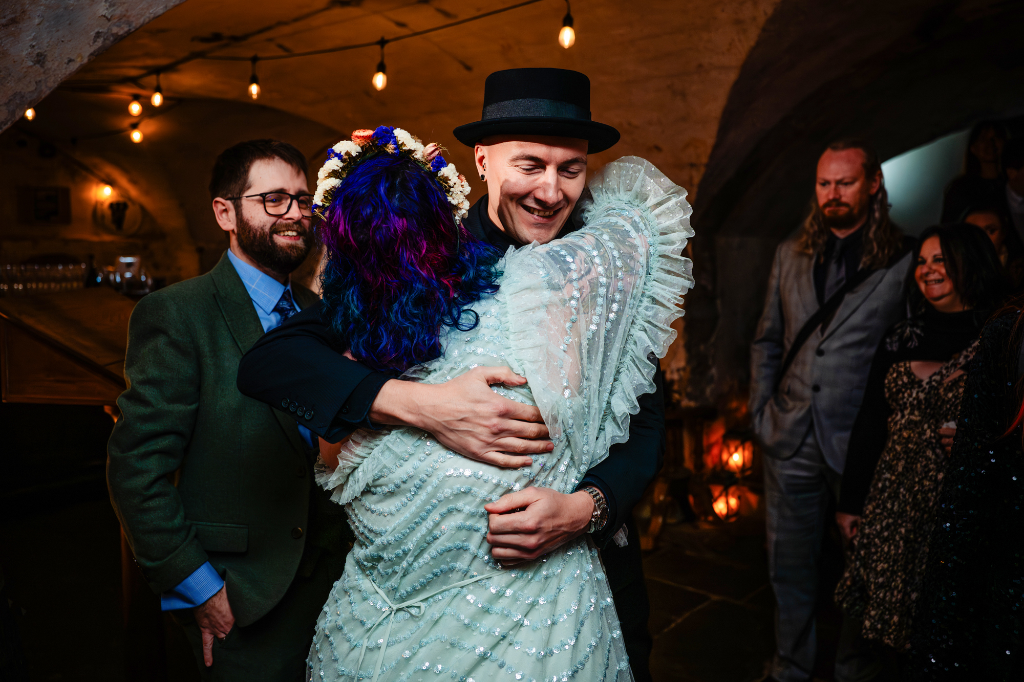 Emotional hug during wedding reception inside candlelit Bristol venue.