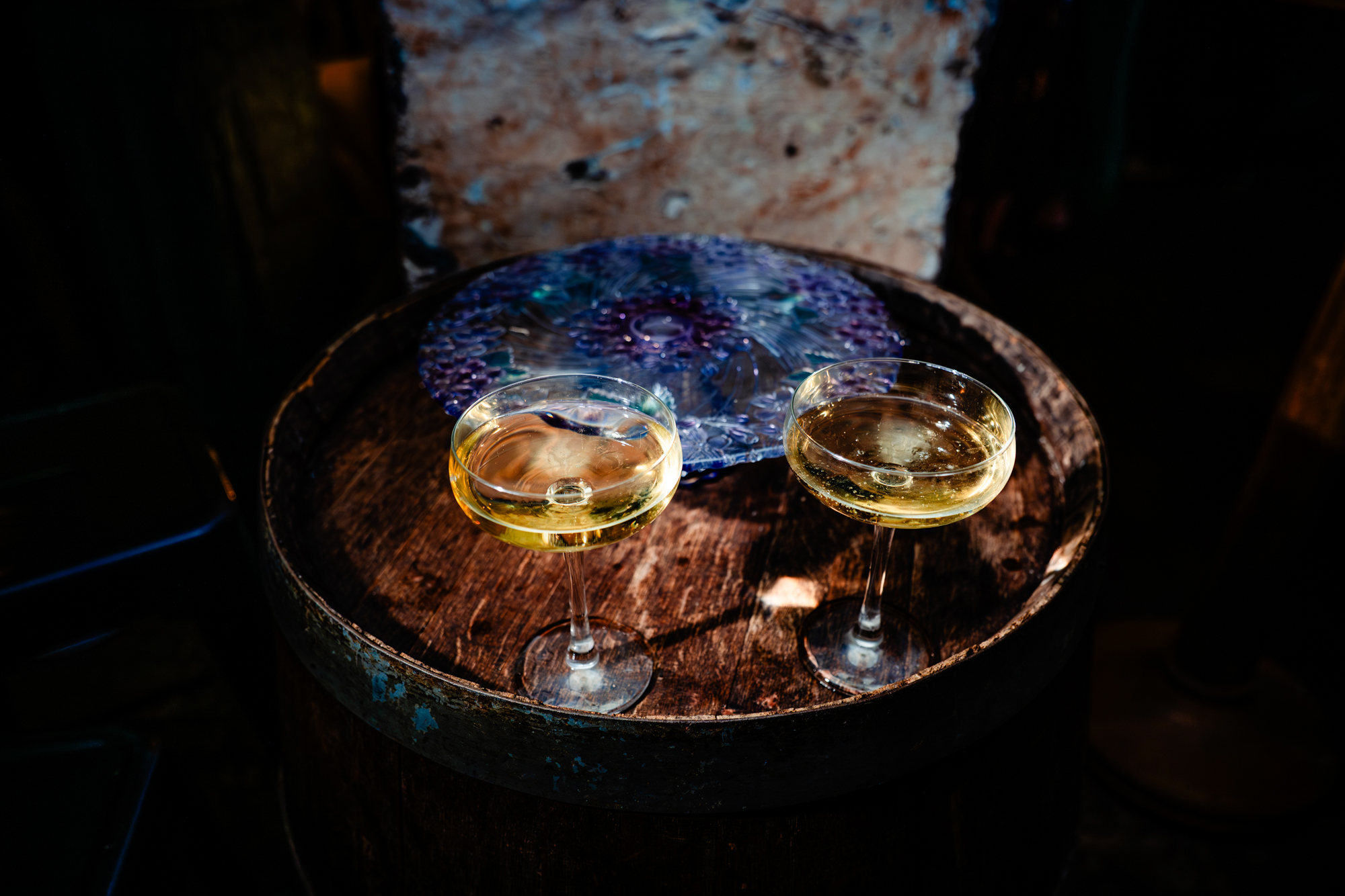 Two champagne coupe glasses on rustic table during wedding reception at The Mount Without Bristol.