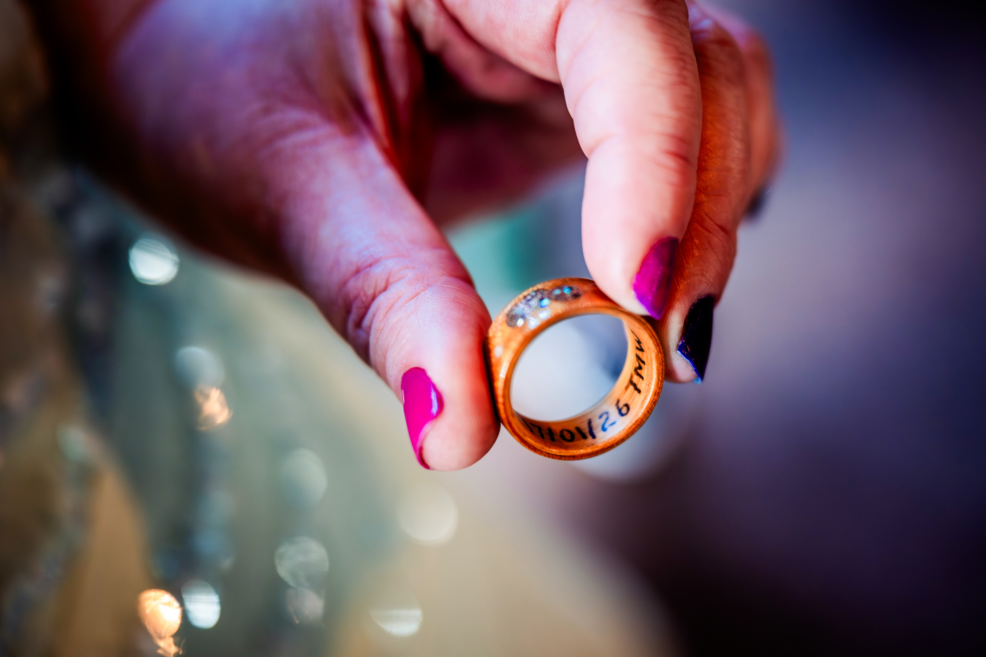 Macro shot of handmade wooden wedding ring with engraved date and subtle gemstones.