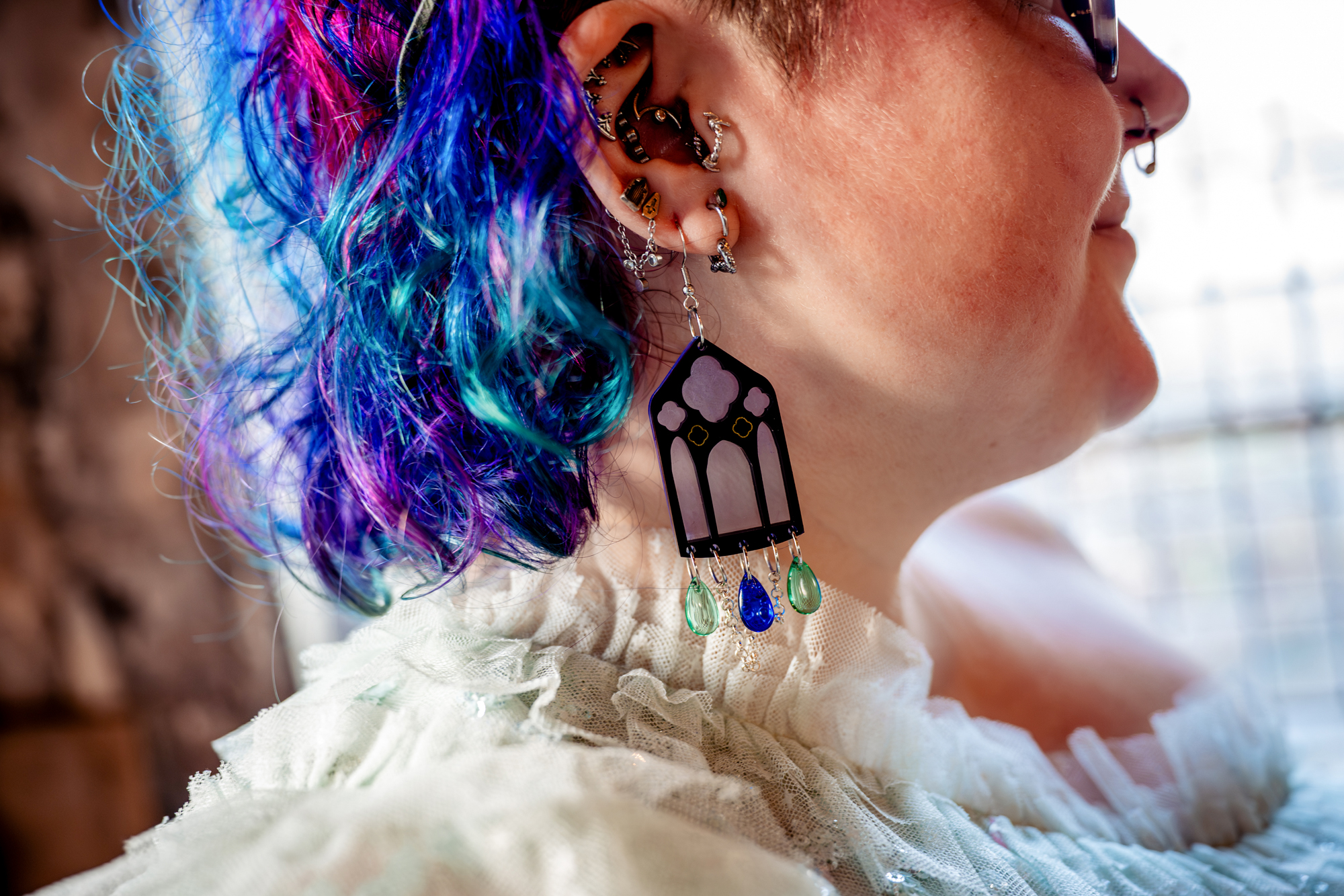 Close-up of colourful hair and statement earrings worn by bride during alternative wedding.