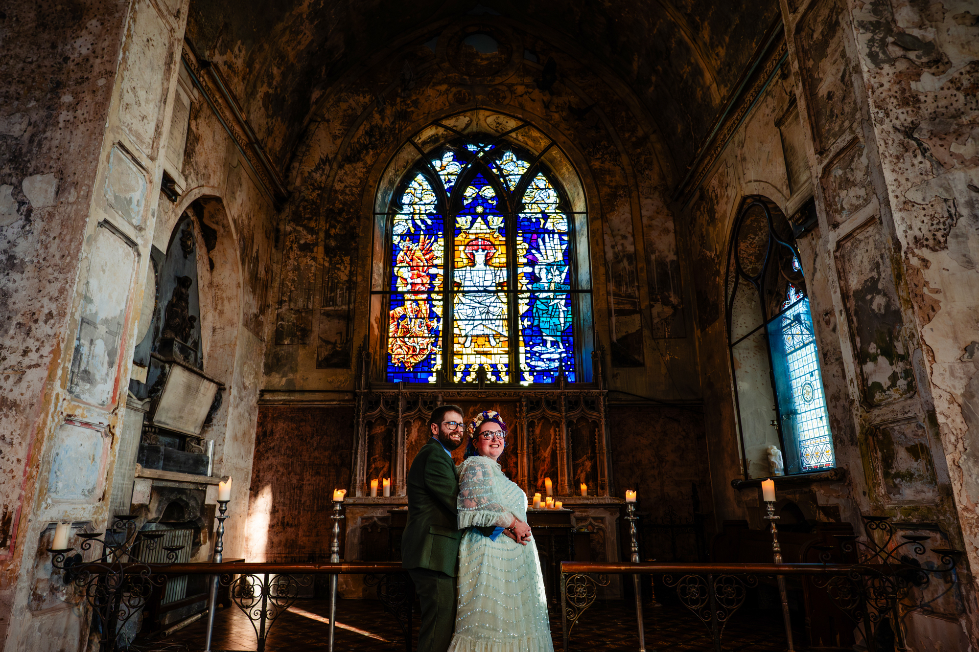 Wide shot of couple standing in chapel space with stained glass at The Mount Without.