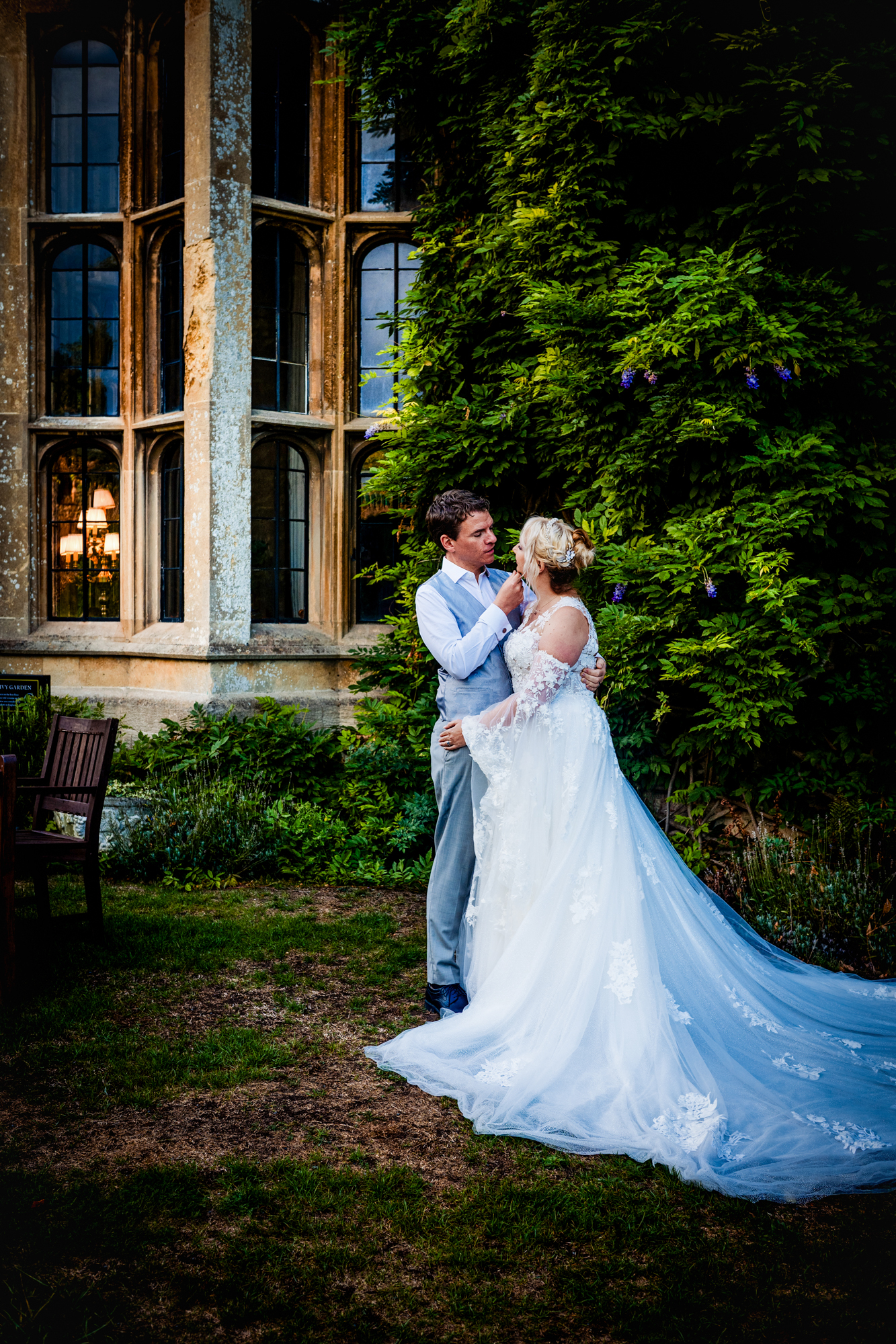 Emma and Steve are standing beside a historic building covered in greenery during their portrait session.