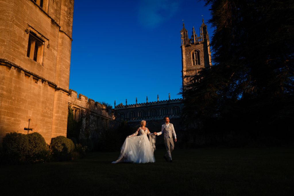 A couple walking hand in hand across castle grounds at dusk, cinematic evening light at Thornbury Castle.