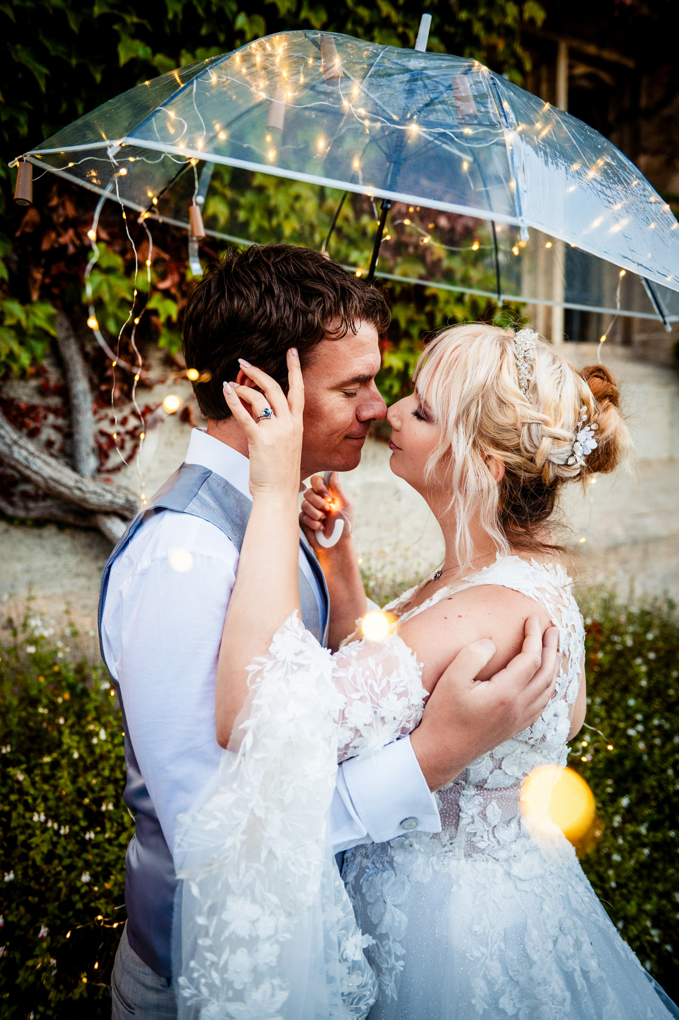 Couple embracing under illuminated umbrella, warm fairy lights creating cosy evening atmosphere at Thornbury Hotel, Bristol.