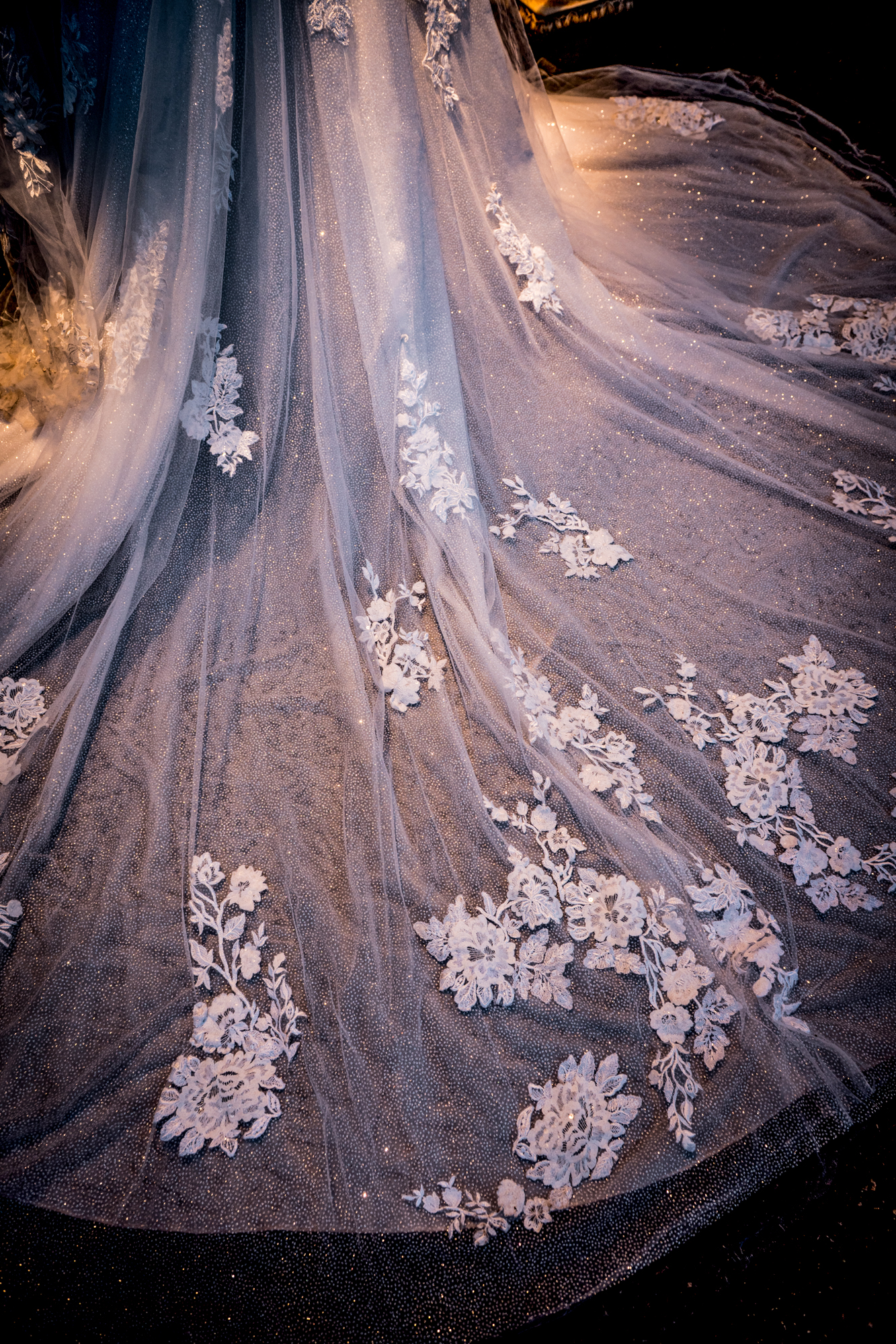 Detailed close-up of lace wedding dress train, delicate embroidery and textured fabric