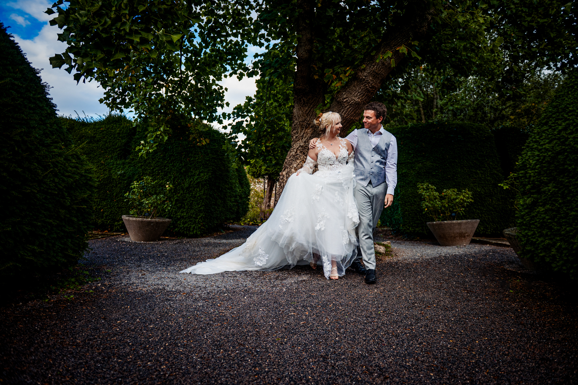 Couple walking closely between tall hedges during a relaxed portrait session at Thornbury Castle.