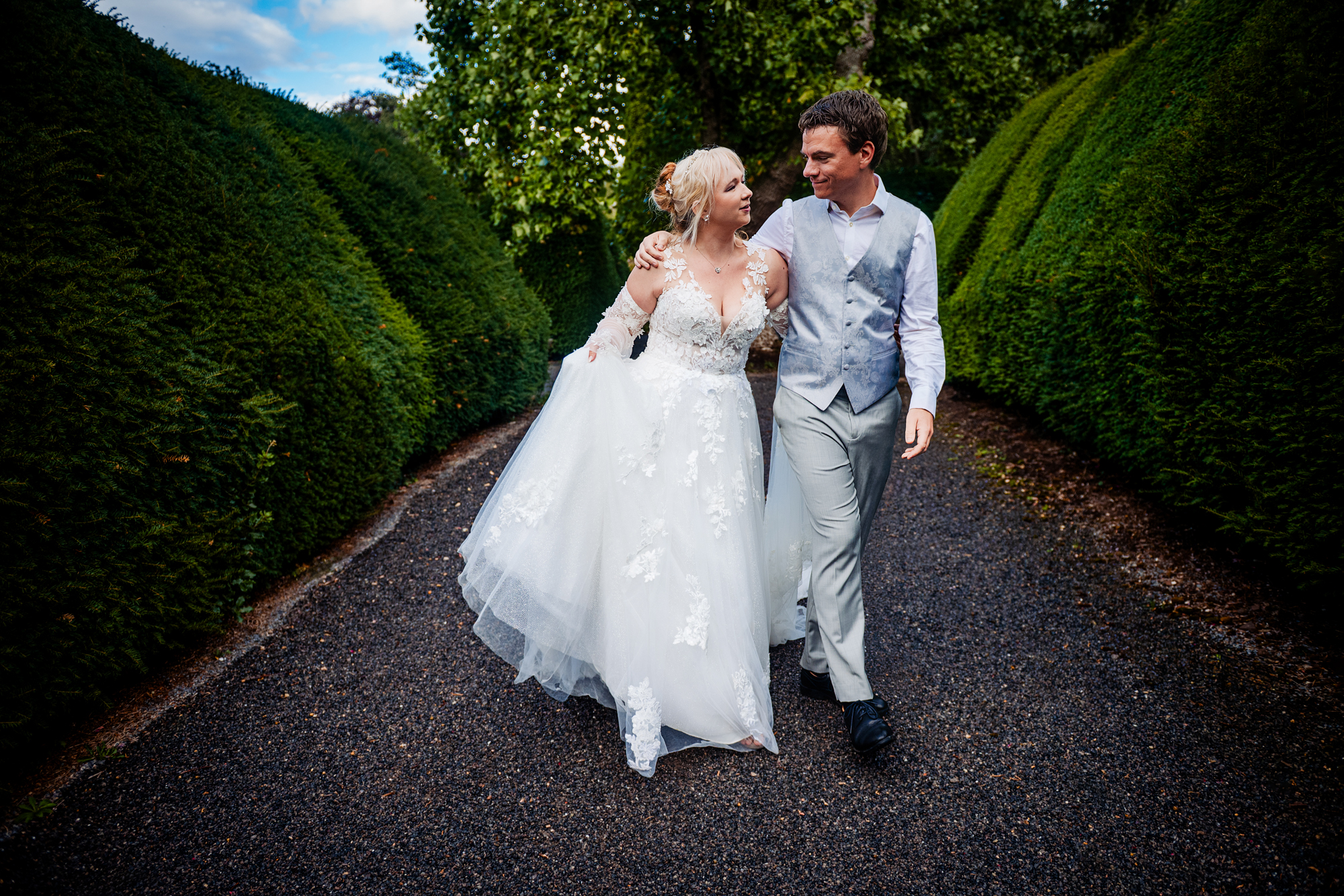 Emma and Steve walking together along a garden path during their Thornbury Castle anniversary session.