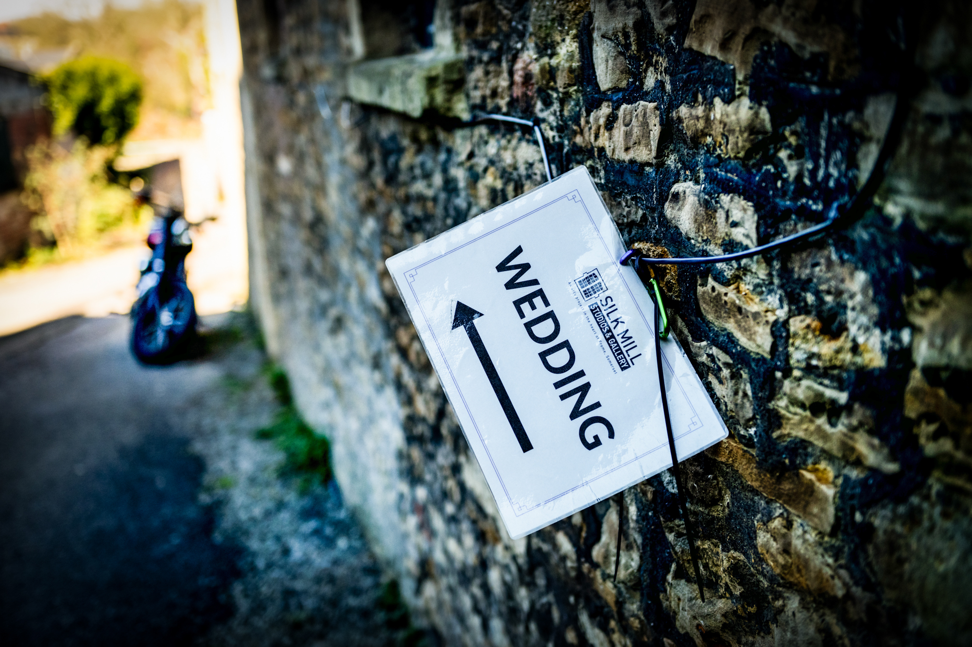 Wedding direction sign tied to a stone wall outside Silk Mill Studios in Frome.