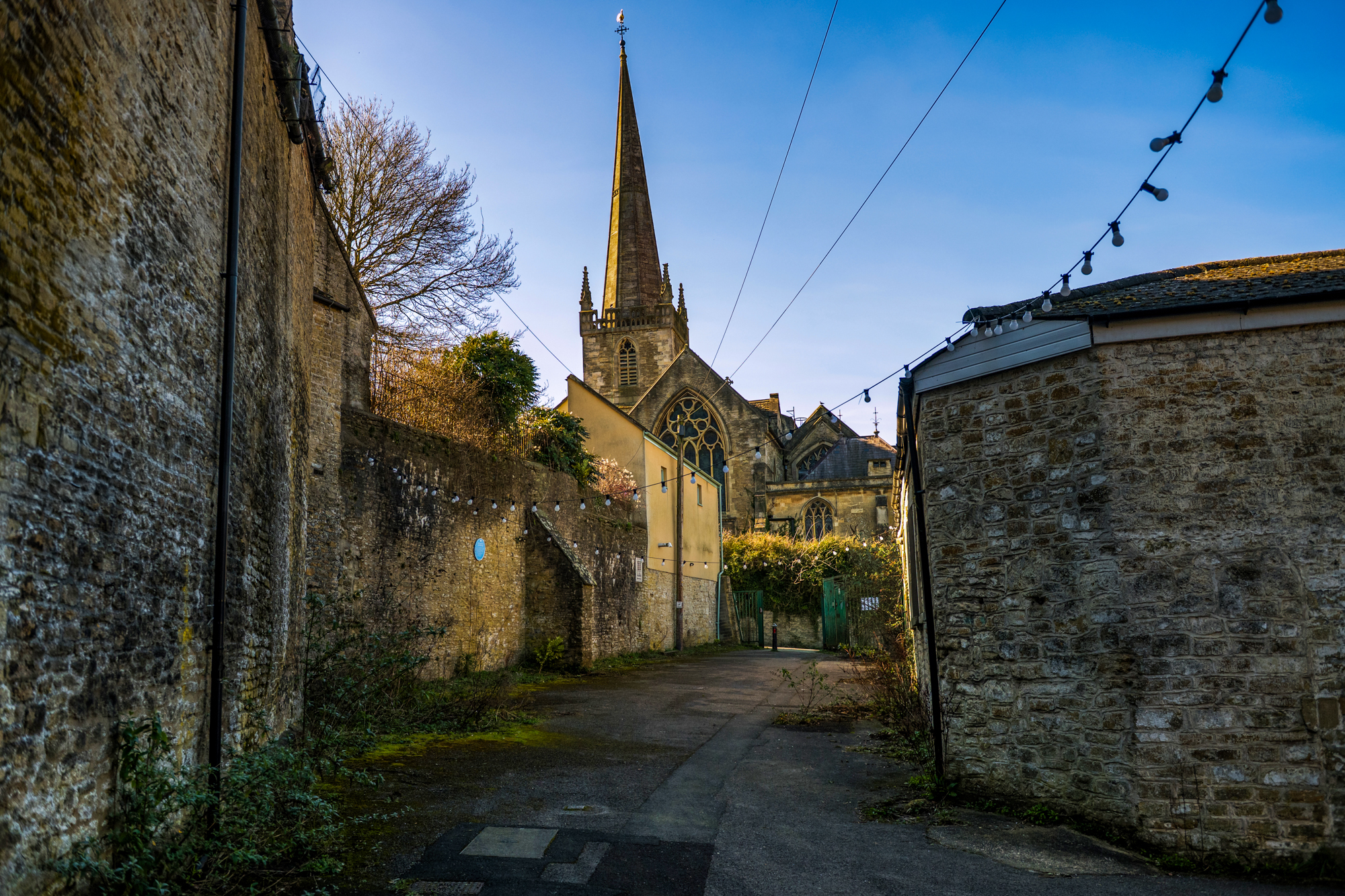 Church spire rising above the stone lane near Silk Mill Studios in Frome.
