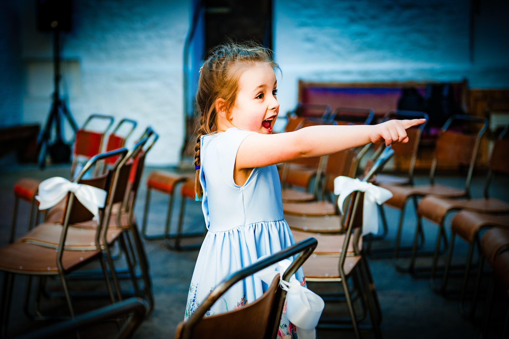 Young flower girl pointing across the ceremony room at Silk Mill Studios in Frome.