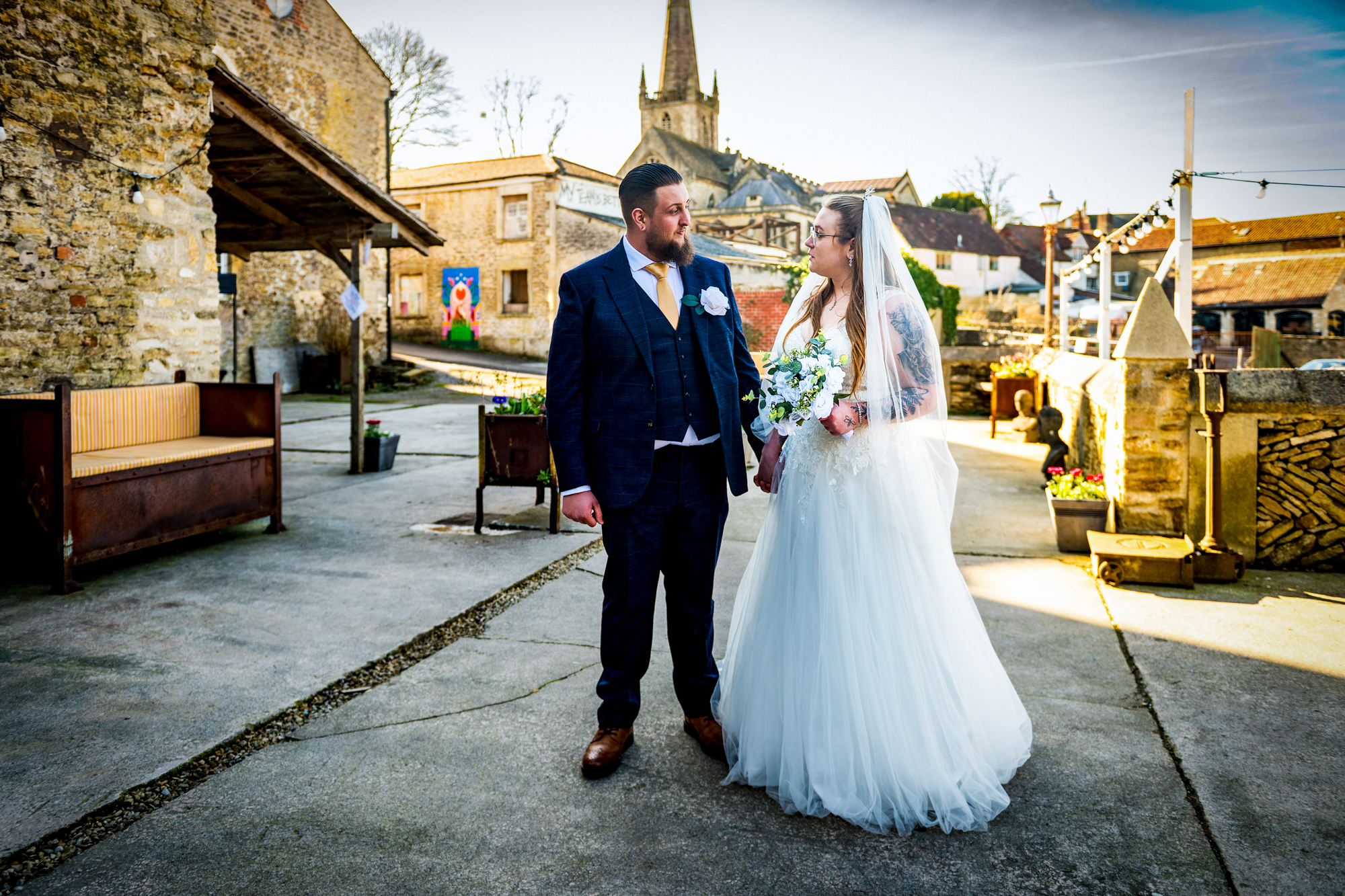 Nat steps through a doorway holding Jon’s hand as her veil and dress trail behind.