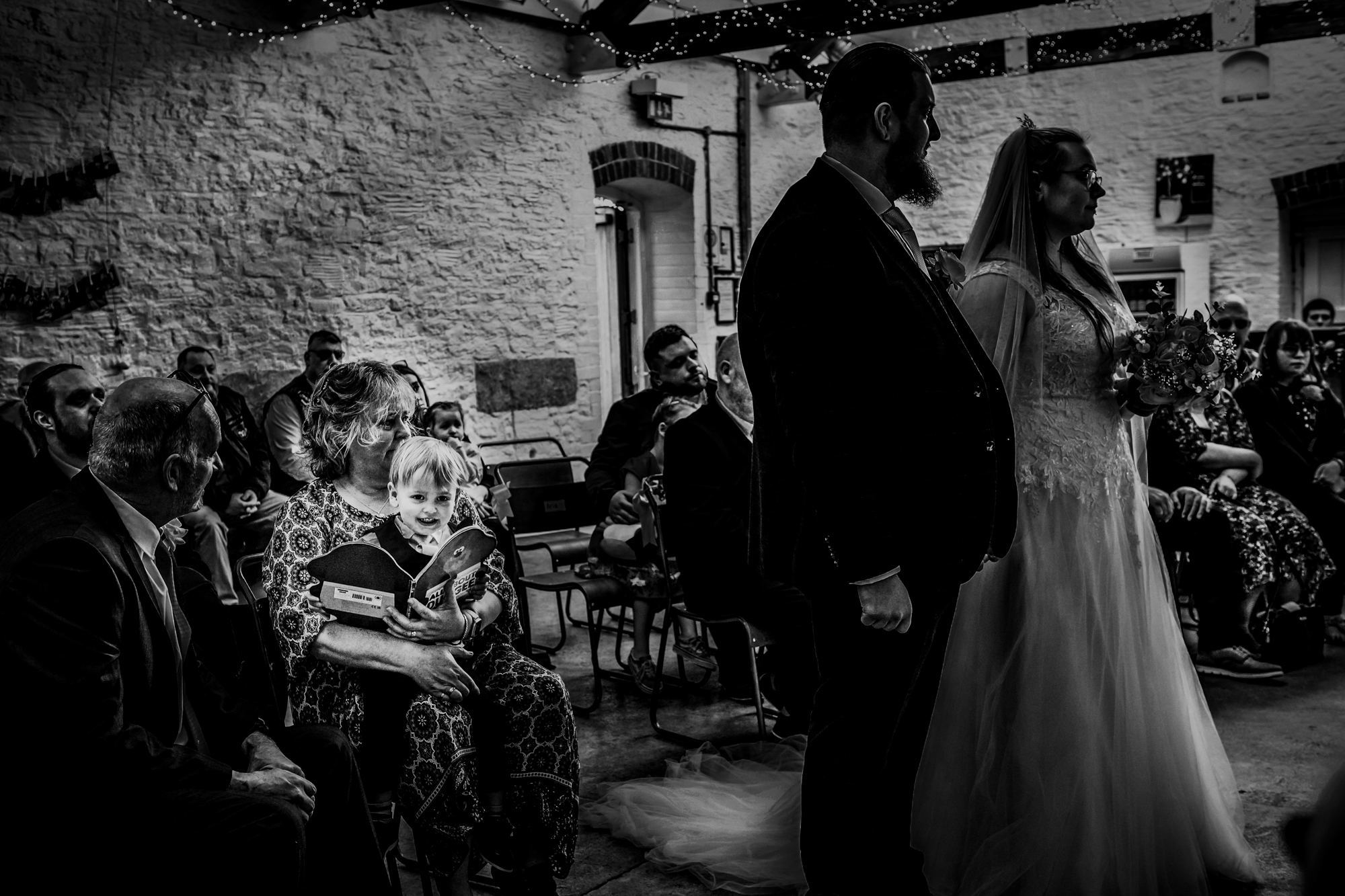 Nat and Jon stand at the front during their ceremony while guests sit behind them.