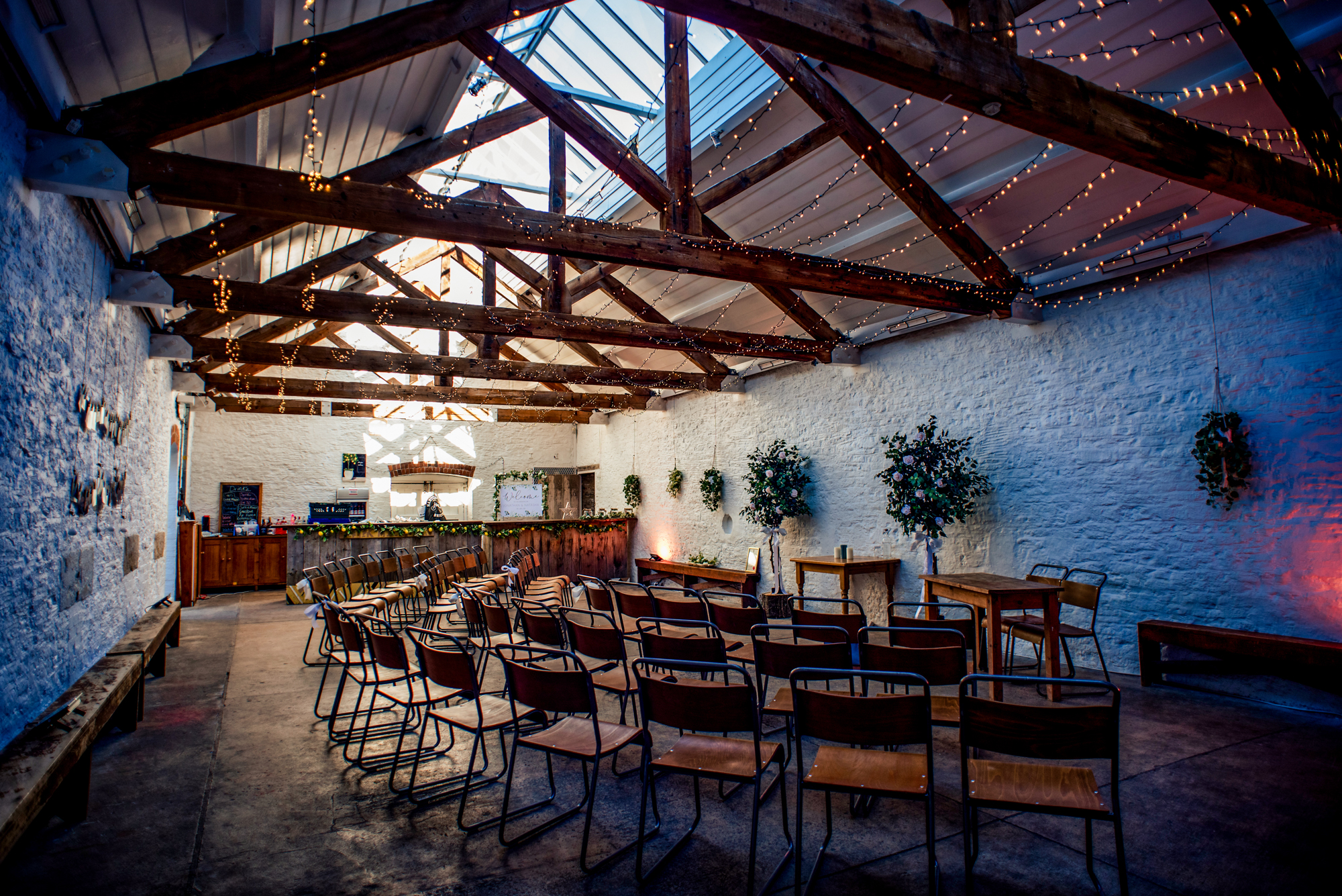 Wide view of the ceremony room at Silk Mill Studios with skylights, fairy lights, and rustic seating.