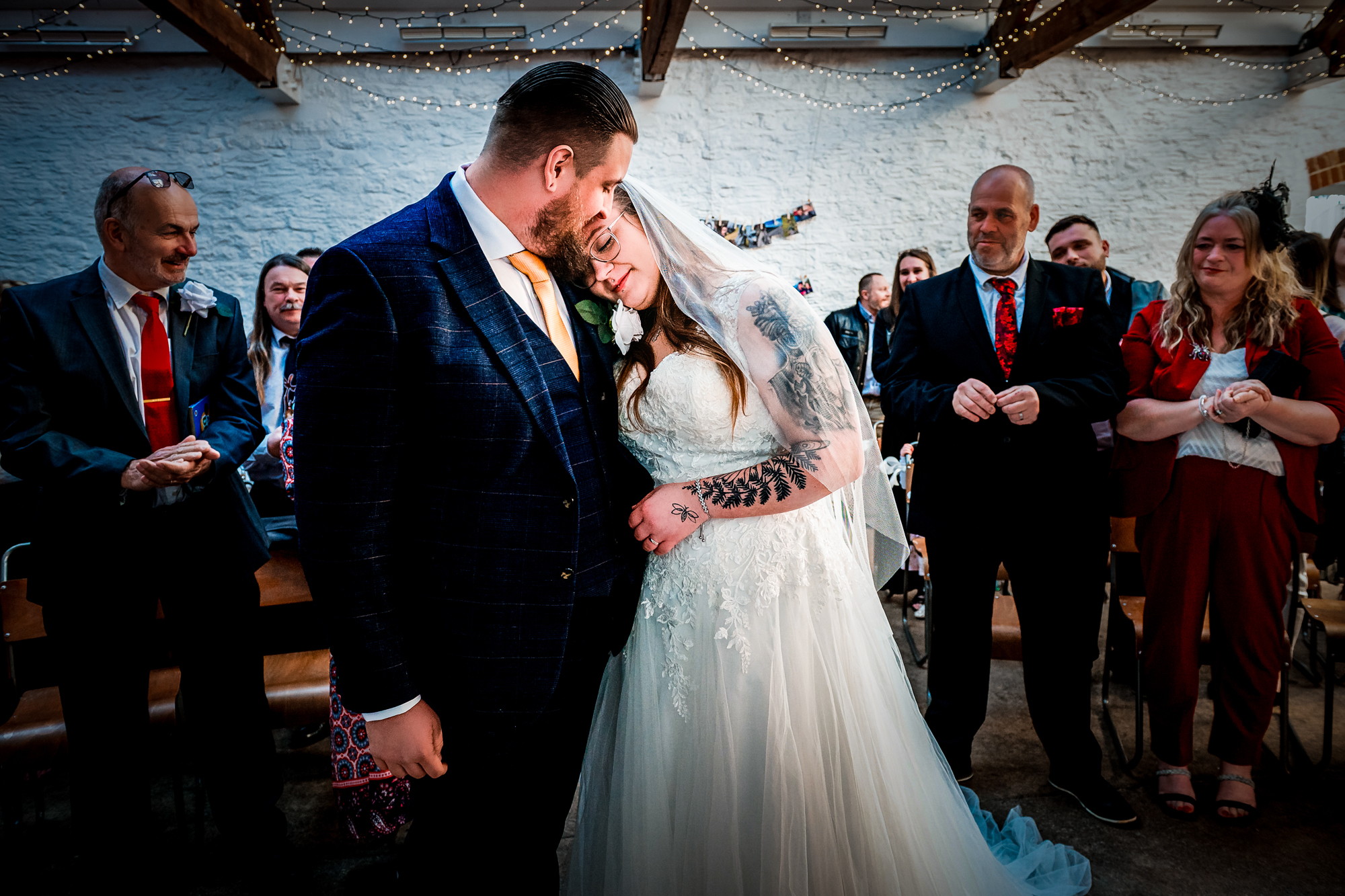 Nat rests her head against Jon after the ceremony as guests watch around them.
